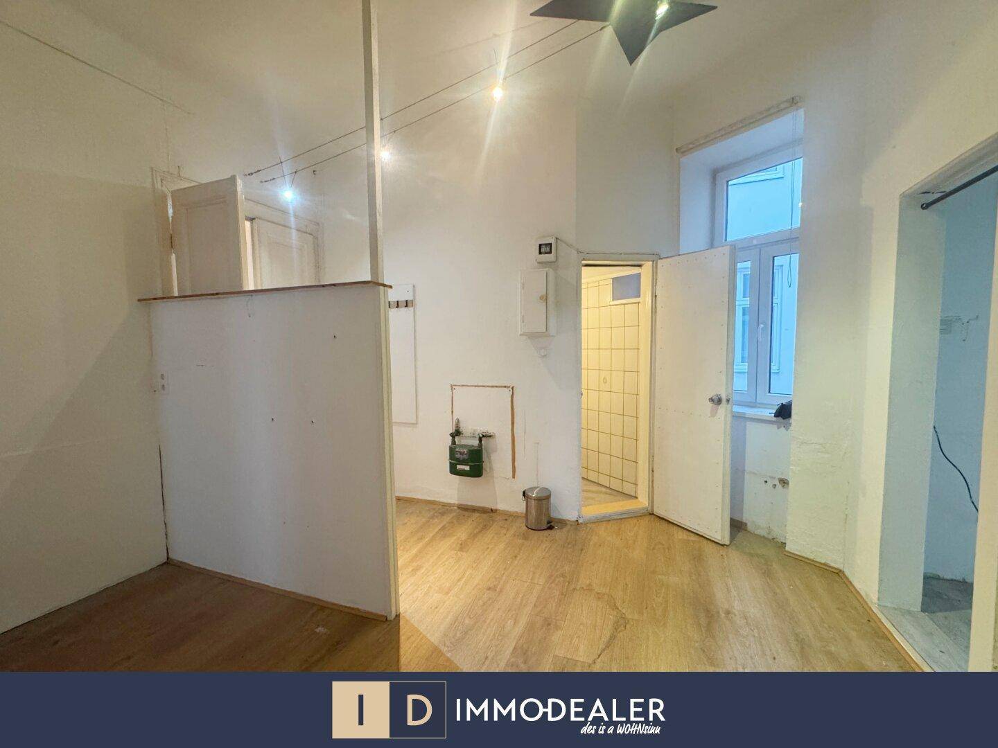 Raum mit Holzboden und Zugang zu einem gefliesten Bereich, ideal für Umbauarbeiten.