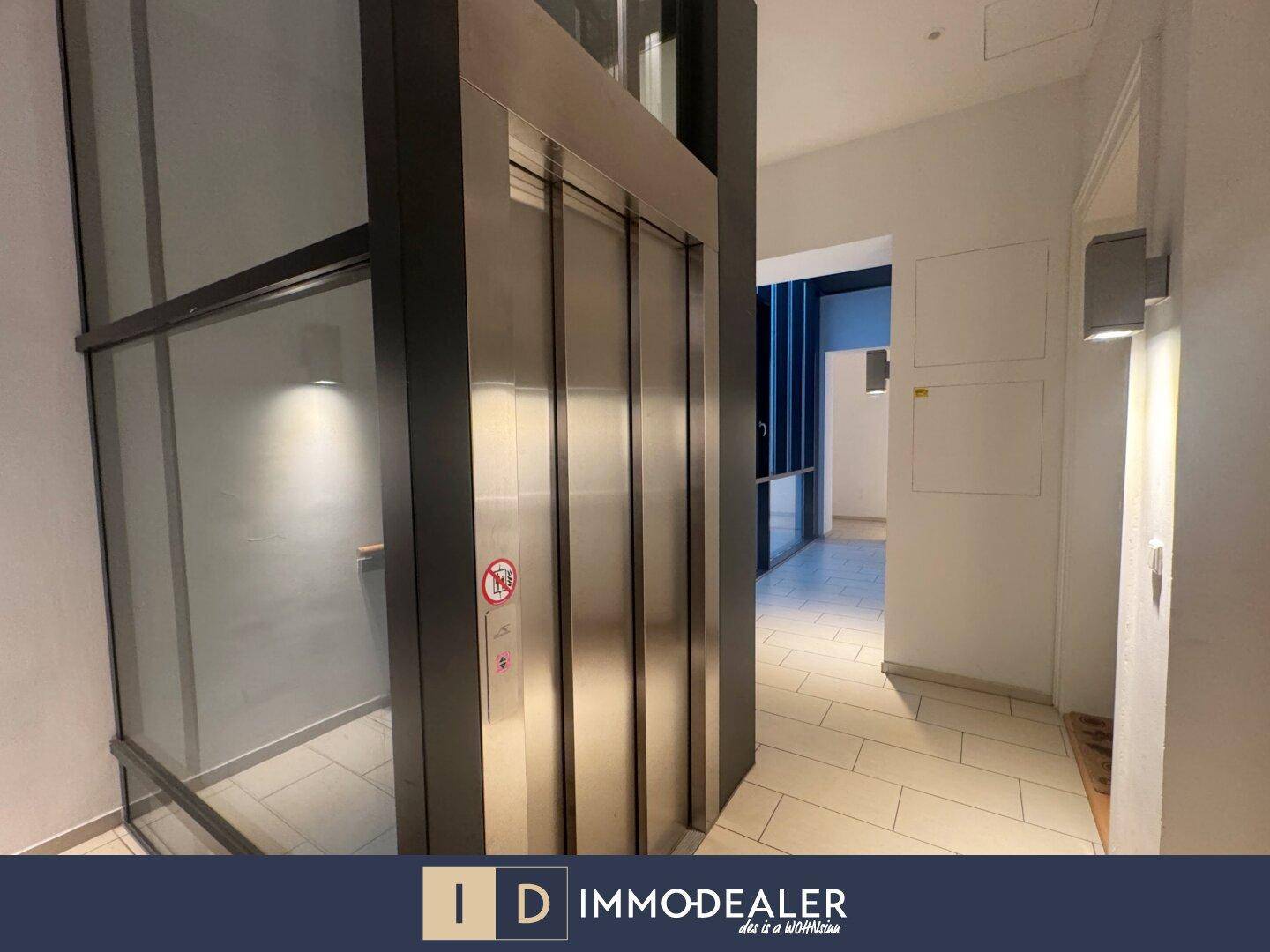 Moderner Aufzug in einem hellen Flur mit Fliesenboden und guter Beleuchtung.
