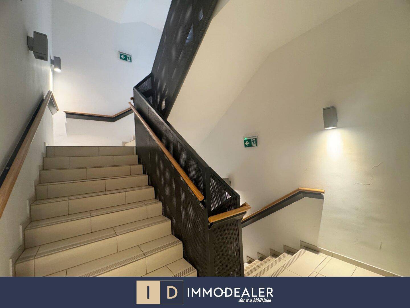 Helles Treppenhaus mit modernen Metallgeländern und Holzhandläufen.
