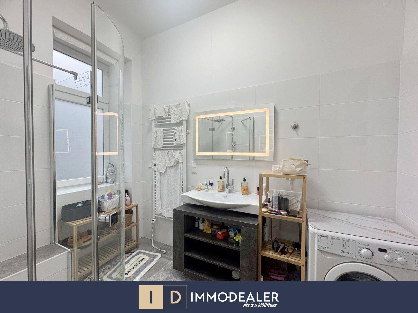 Modernes Badezimmer mit großer Duschkabine, Waschbecken und integrierter Waschmaschine.