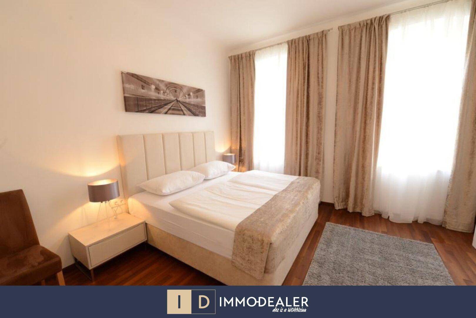 Gemütliches Schlafzimmer mit großem Bett, Nachttischen und Vorhängen an den Fenstern.