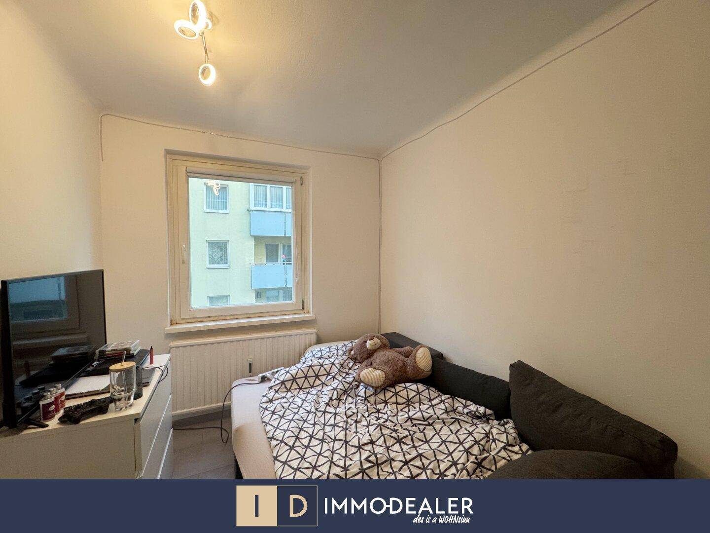 Schlafzimmer mit Einzelbett, Fernseher und Fenster mit Blick auf die Umgebung.