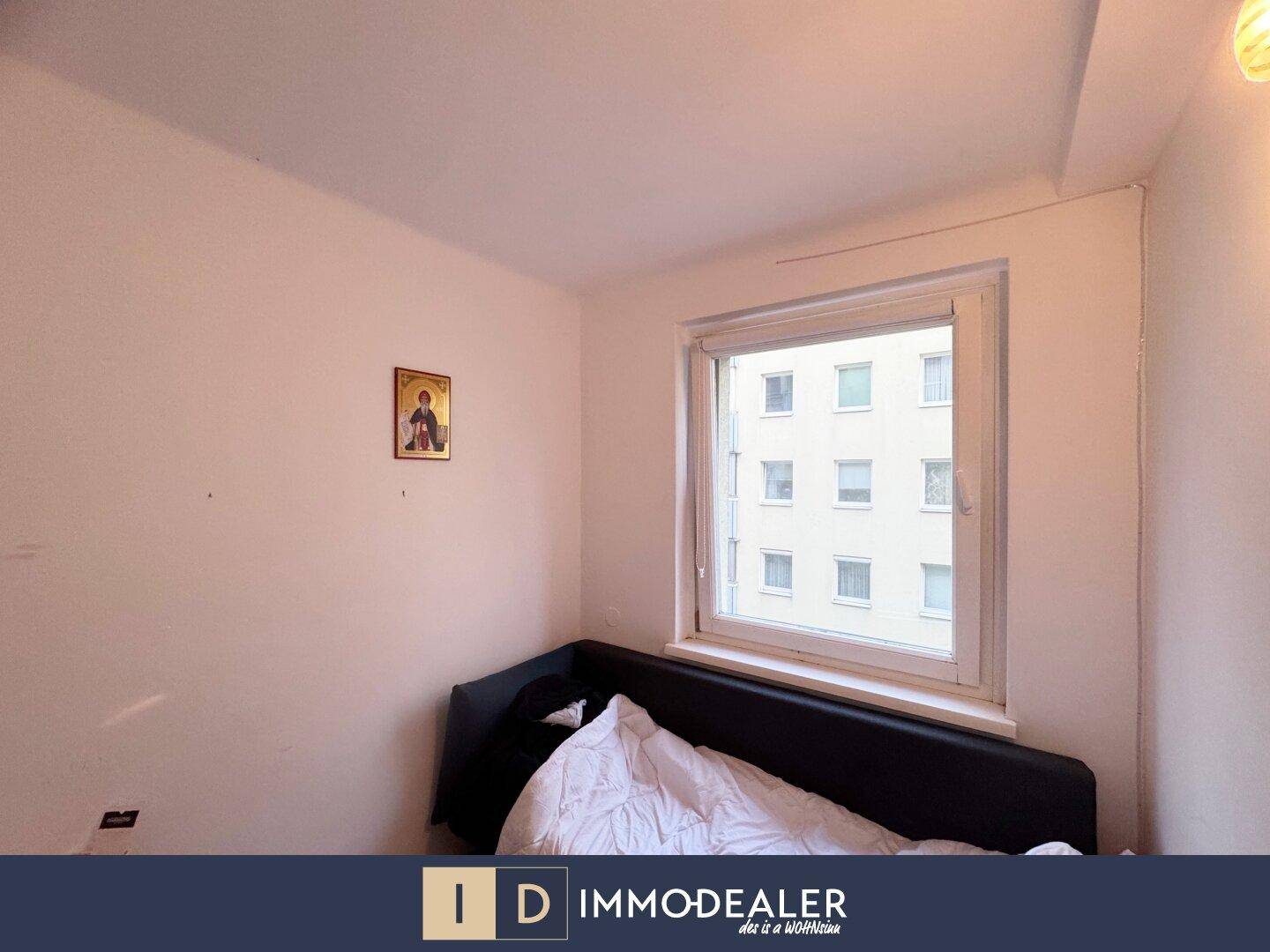 Helles Schlafzimmer mit Bett und großem Fenster, das viel Tageslicht hereinlässt.