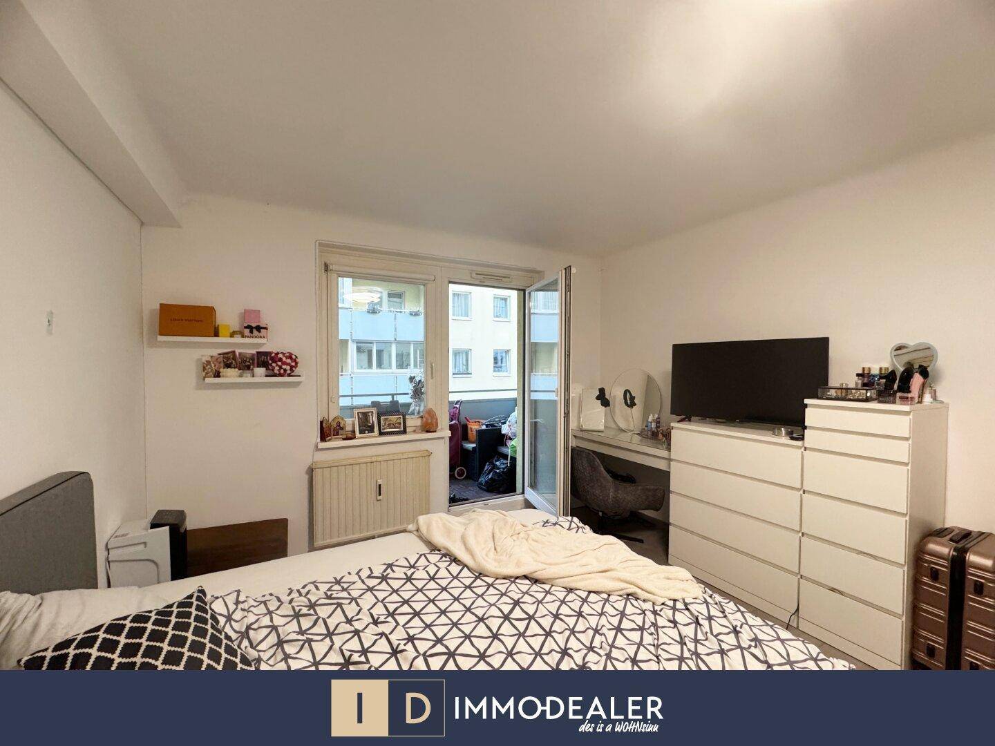 Schlafzimmer mit Doppelbett, Kommode und direktem Zugang zum Balkon.