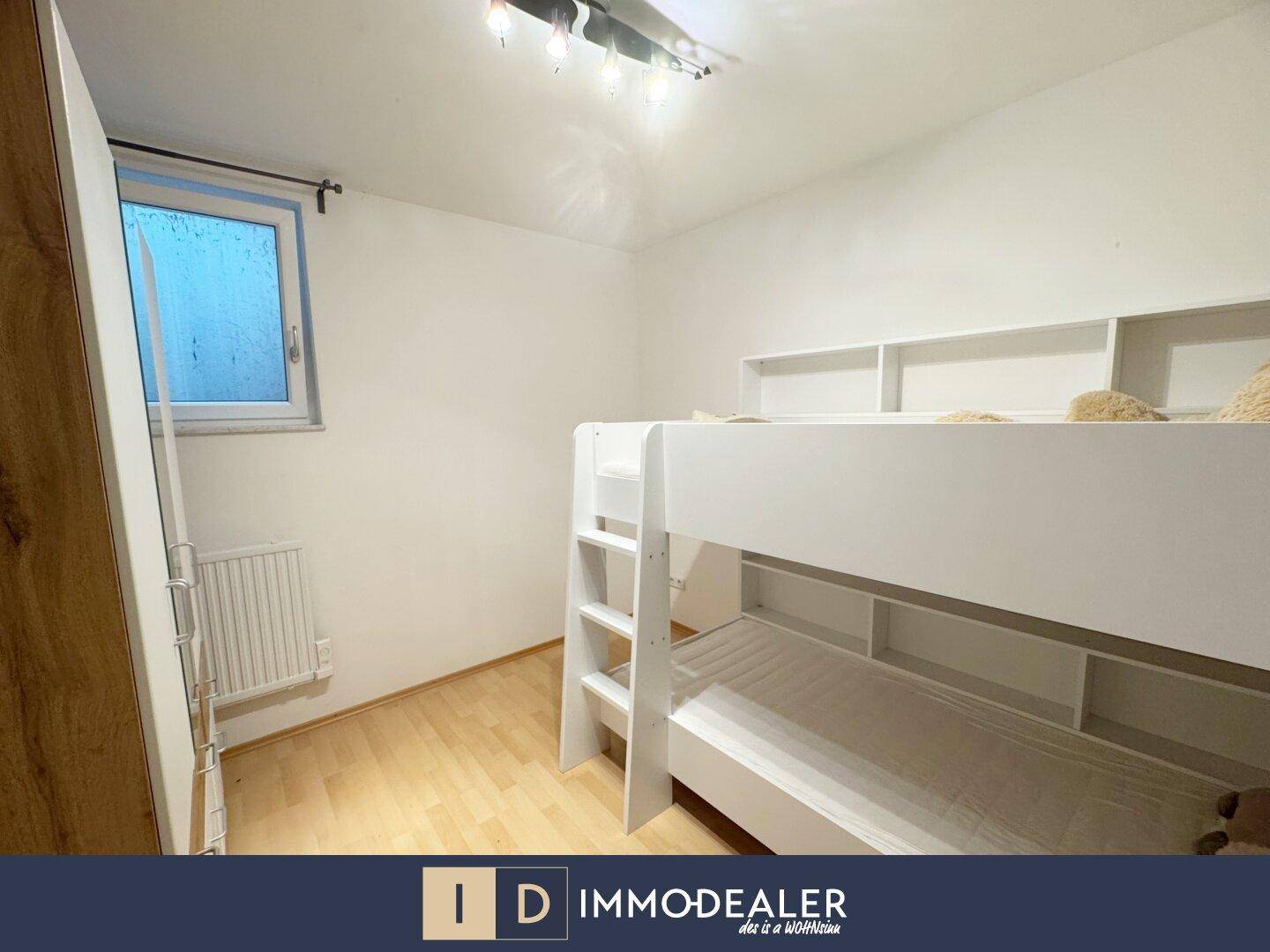 Kinderzimmer mit Etagenbett und Holzfußboden, ausgestattet mit einem Fenster für Tageslicht.