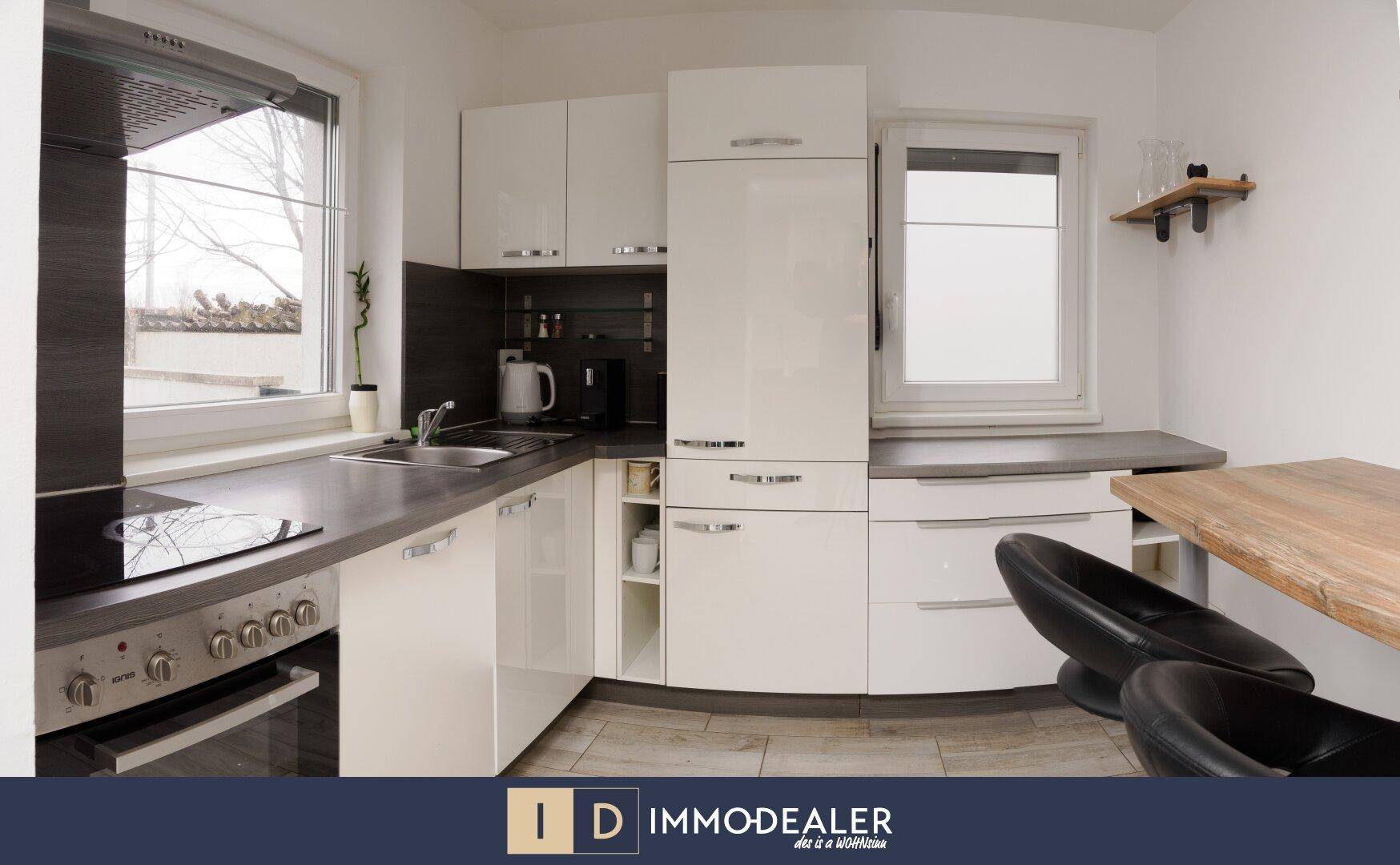 Moderne Einbauküche mit weißen Hochglanzfronten, Kochfeld und integriertem Backofen und Kühlschrank.