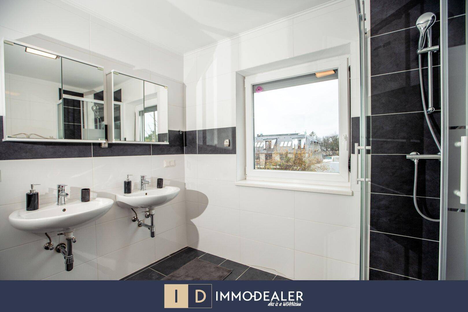 Modernes Badezimmer mit Doppelwaschbecken, großer Dusche und Fenster für natürliches Tageslicht.