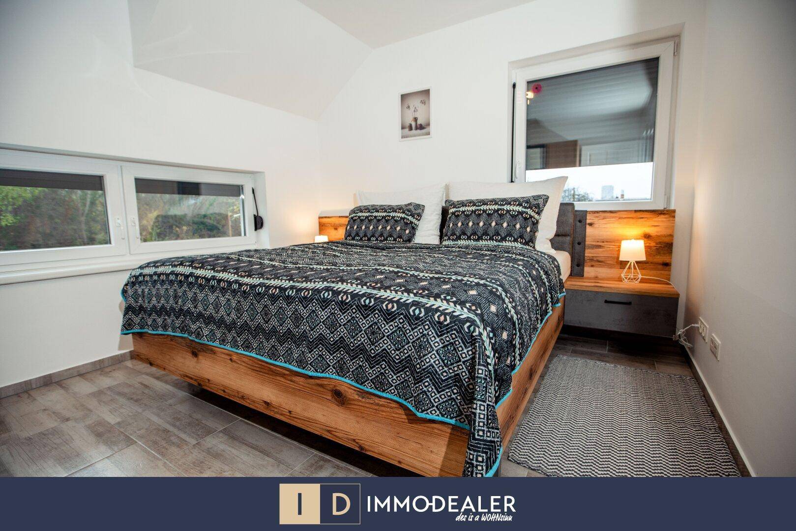 Schlafzimmer mit modernem Doppelbett, Holzakzenten und Fenster für natürliche Belichtung des Raumes.