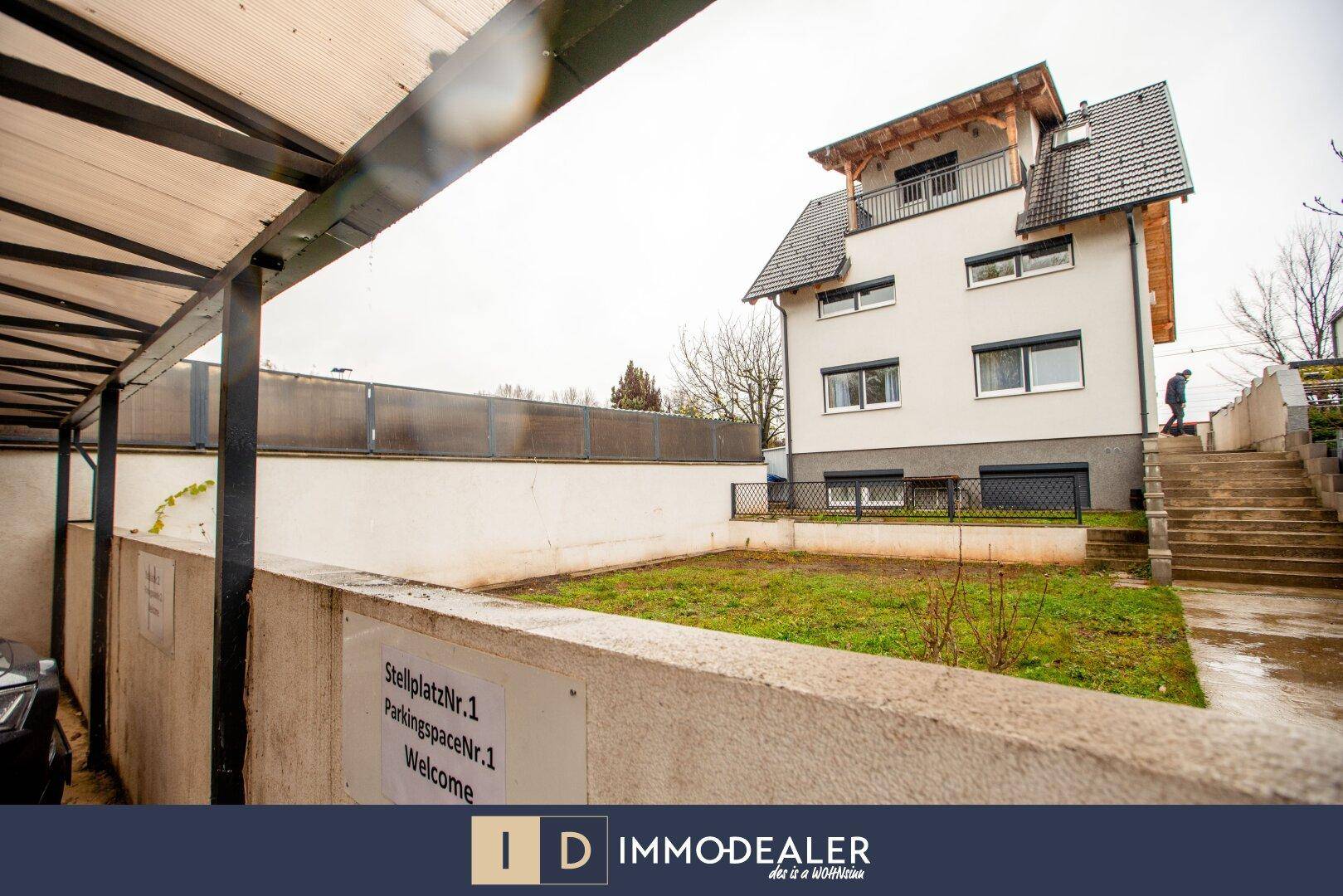 Außenansicht des Gebäudes mit überdachtem Stellplatz und Zugangstreppe zum Eingangsbereich.