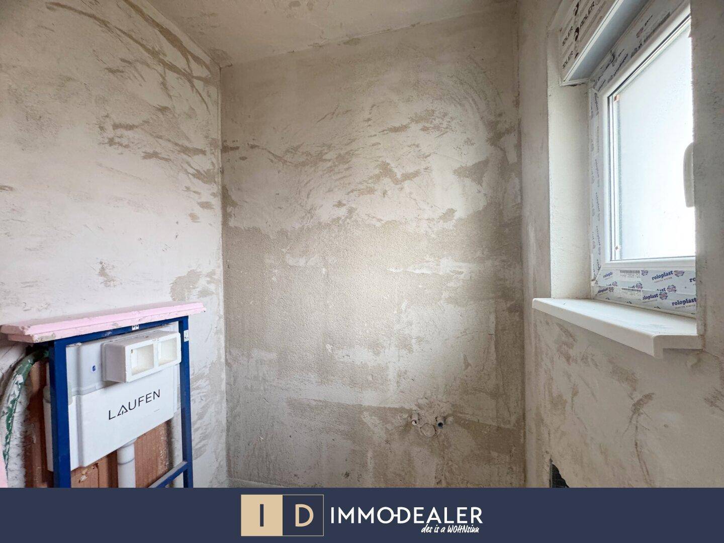 Rohbau eines WCs oder kleinen Badezimmers mit sichtbarem Spülkasten und einem Fenster.