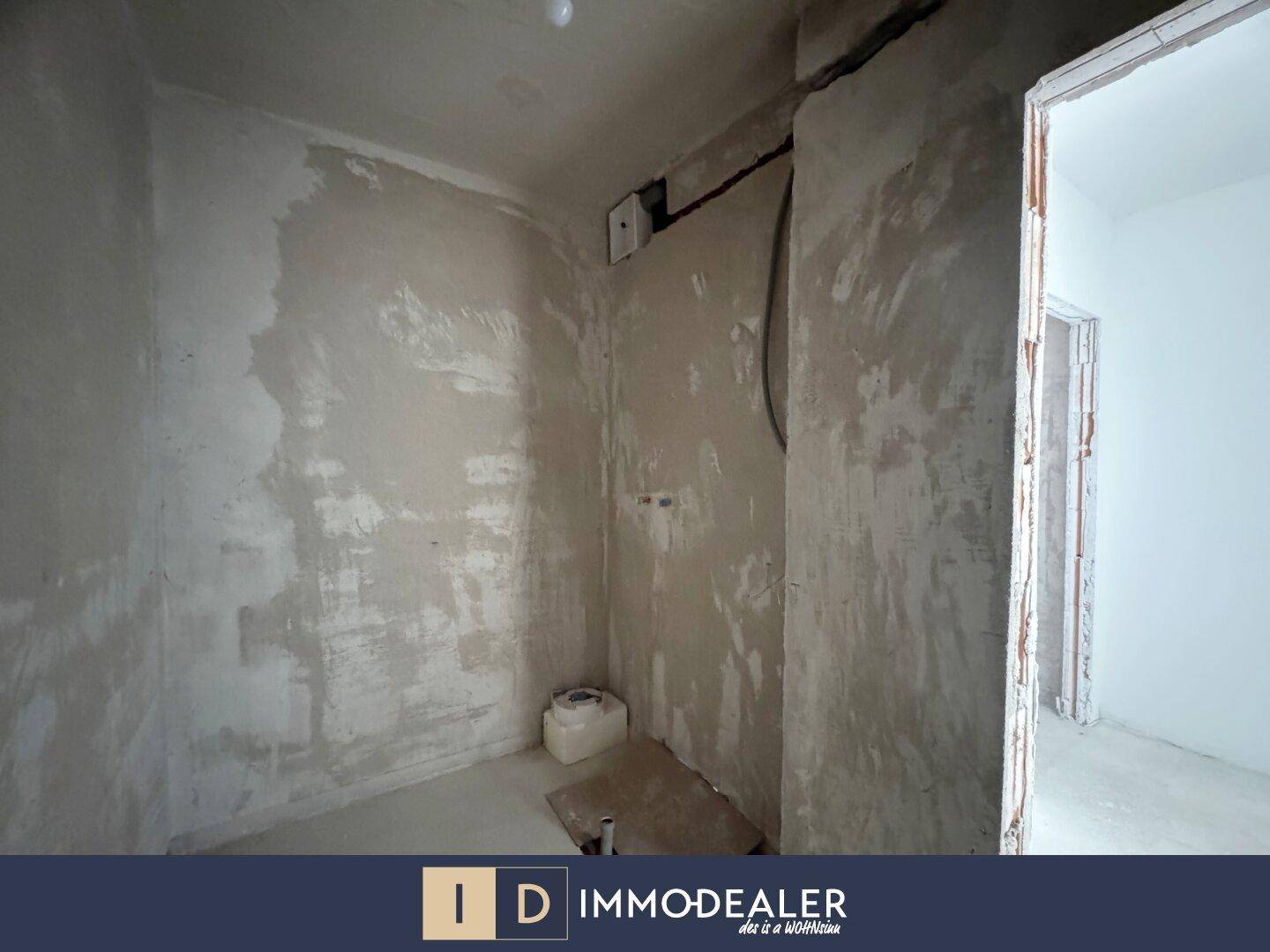 Kleiner Raum im Rohbau, wahrscheinlich ein Badezimmer, mit unfertigen Wänden und sichtbaren Installationen.