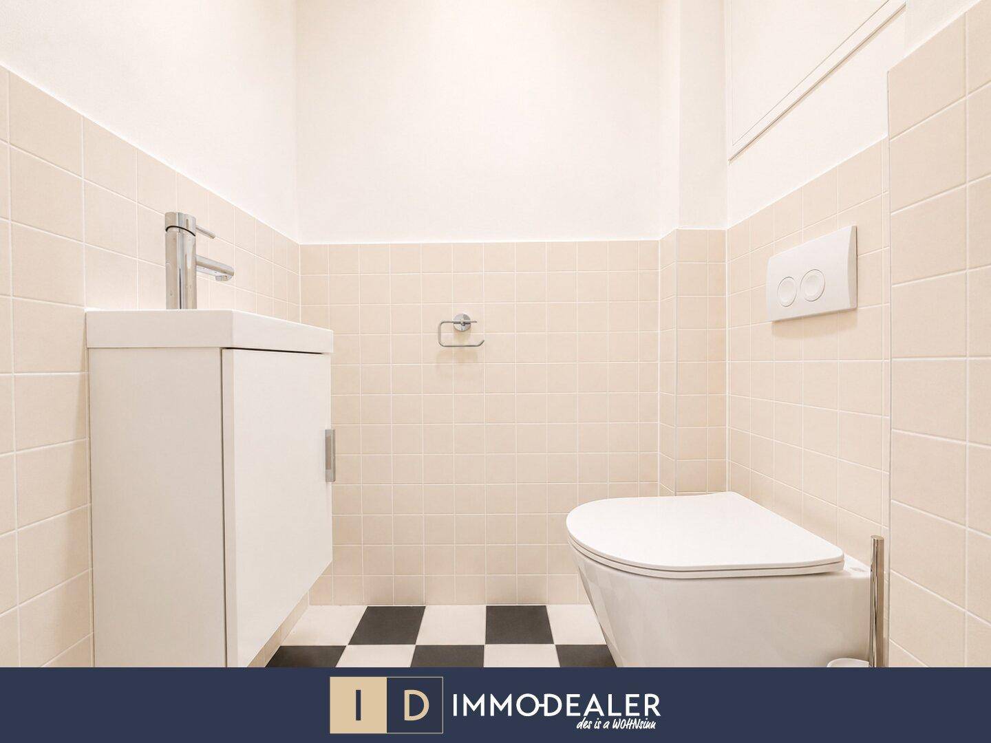 Modernes Gäste-WC mit Wand-WC, kleinem Waschbecken und schwarz-weißem Fliesenboden.