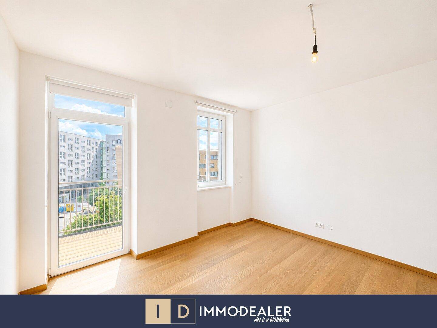 Helles Schlafzimmer mit Parkettboden und Zugang zu einem französischen Balkon.