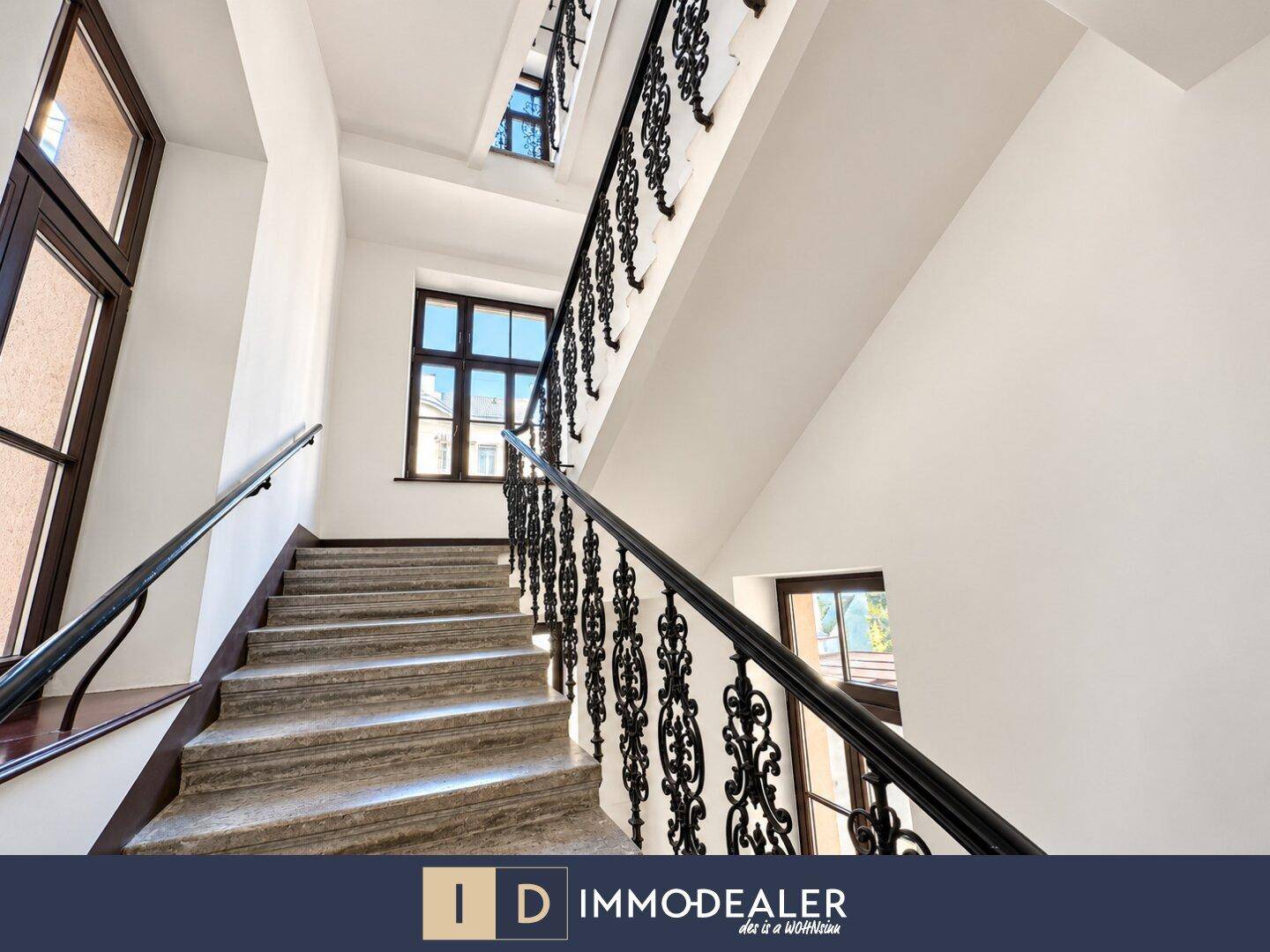 Elegantes Treppenhaus mit schmiedeeisernem Geländer und Steinstufen.