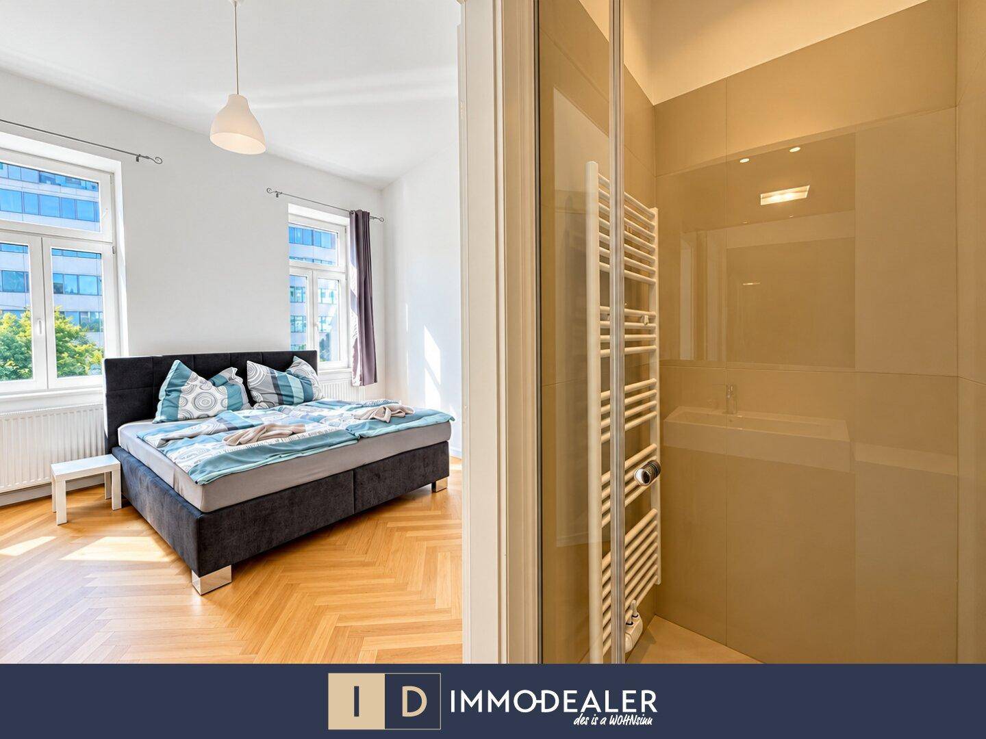 Schlafzimmer mit Doppelbett und Blick in ein modernes Badezimmer mit Dusche.