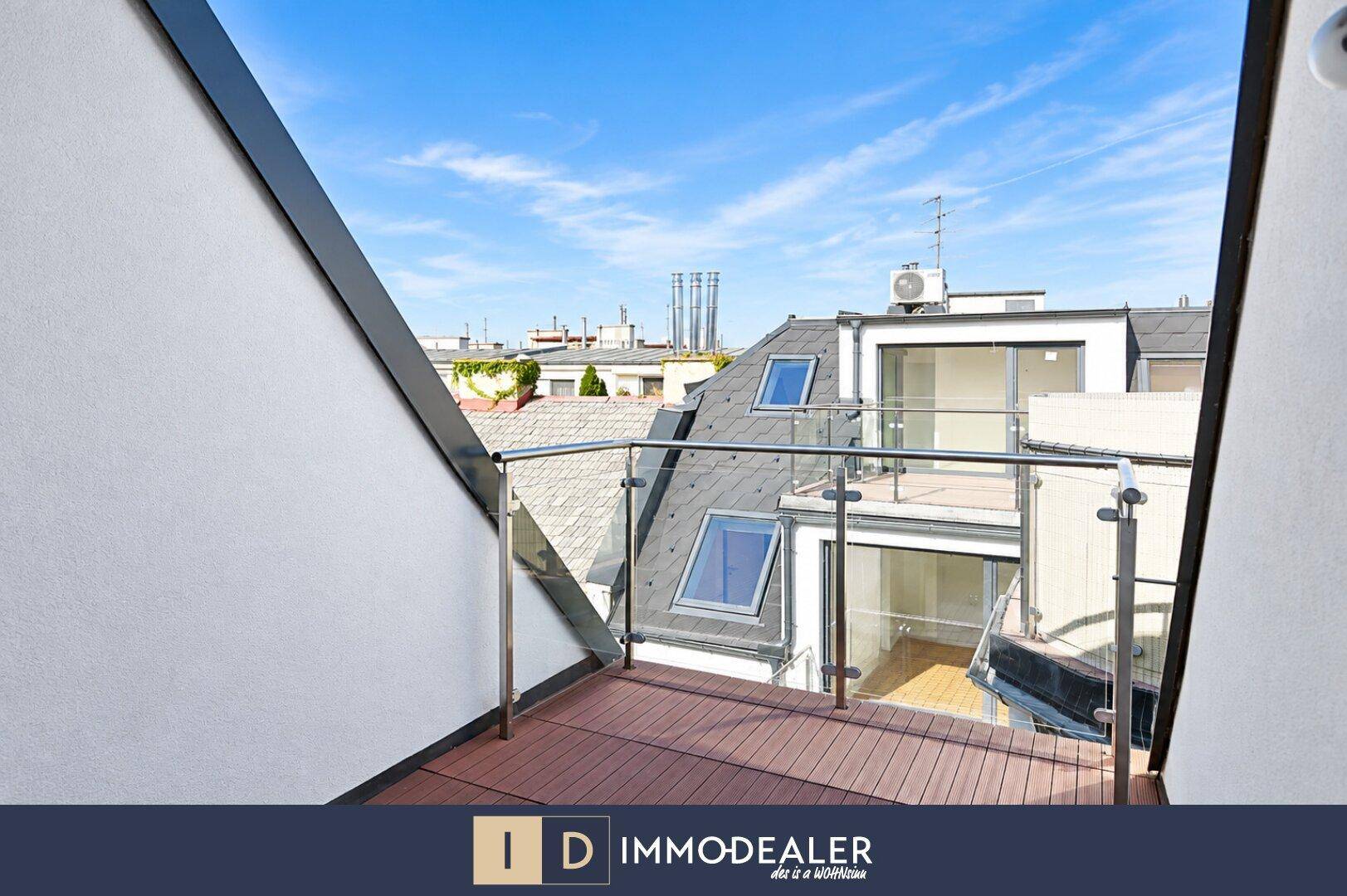 Moderner Balkon mit Holzbelag und Glasgeländer bietet einen weiten Blick über die Dächer der Stadt.