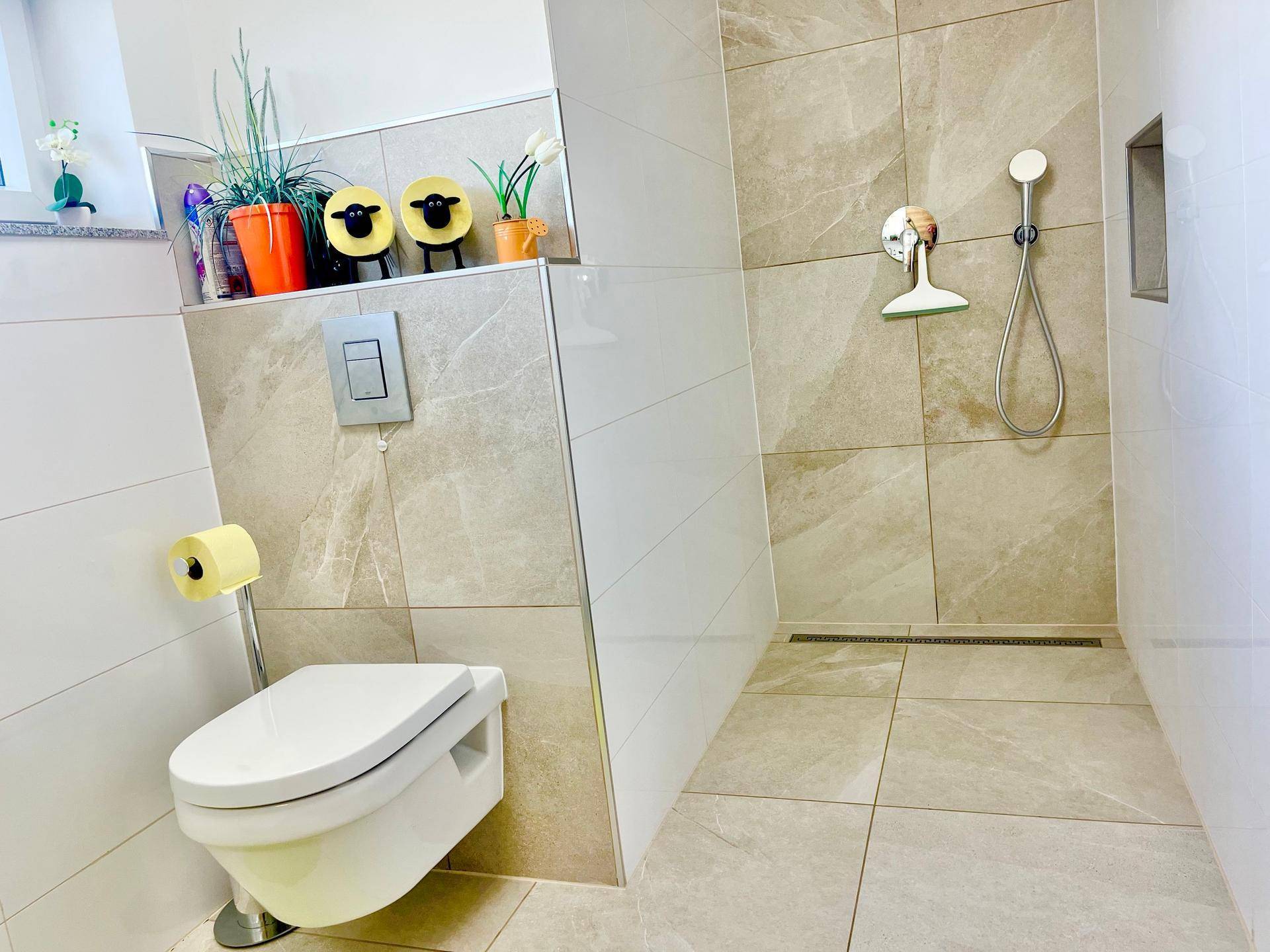 Modernes Badezimmer mit begehbarer Dusche und Wand-WC, hell gefliest.