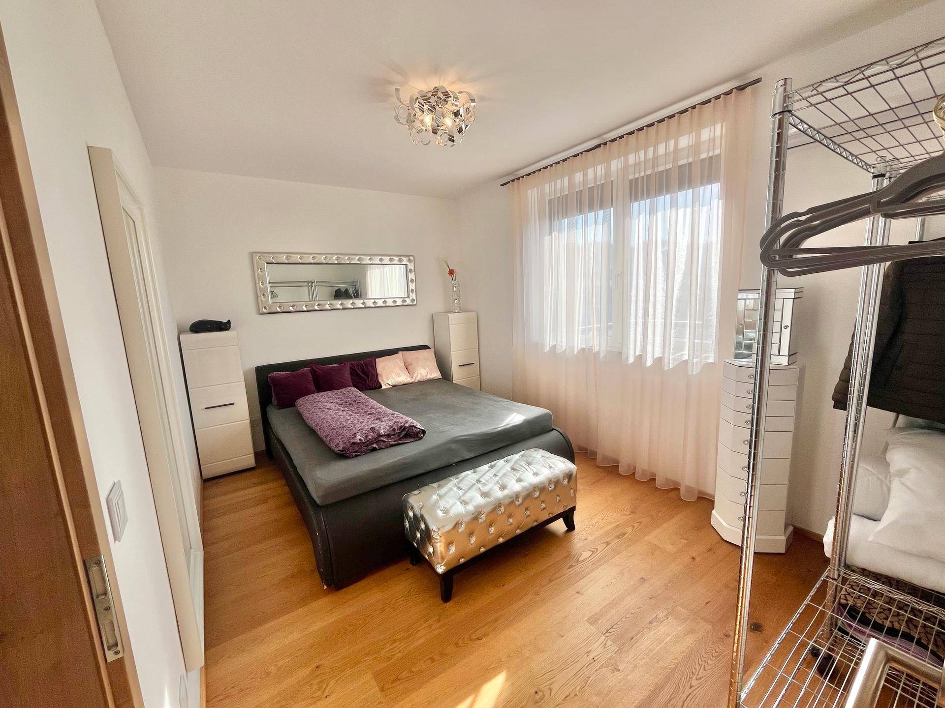 Gemütliches Schlafzimmer mit Doppelbett, Holzboden und offenem Kleiderschrank.