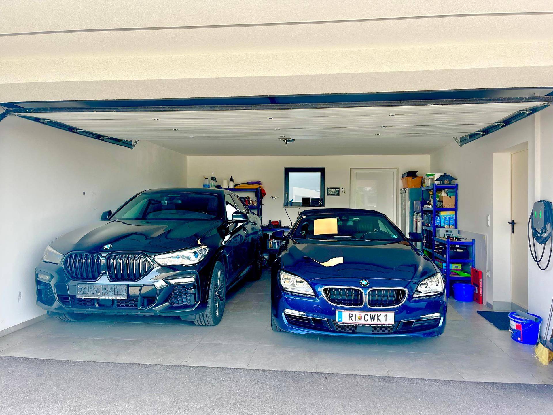 Geräumige Doppelgarage mit zwei Fahrzeugen und einer Ladestation für Elektroautos.