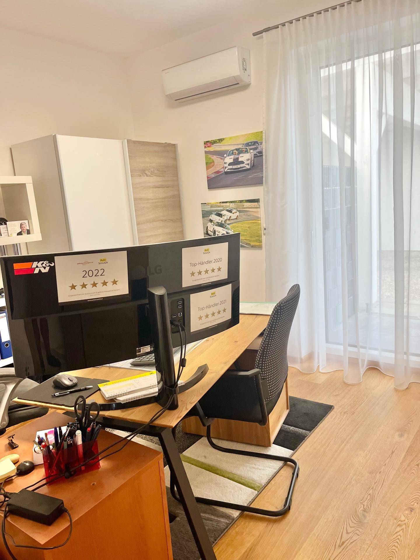 Helles Arbeitszimmer mit großem Fenster, transparenten Vorhängen und Klimaanlage für angenehmes Raumklima.