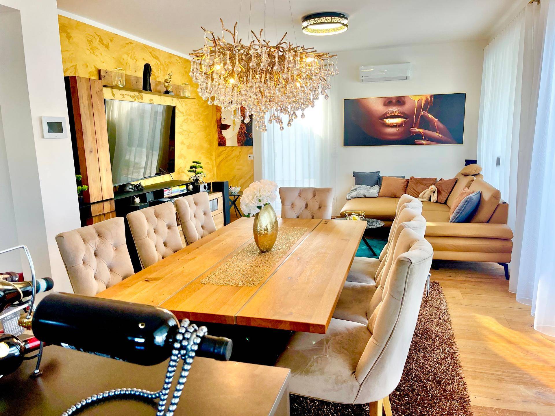 Helles Wohn- und Esszimmer mit elegantem Kronleuchter, Holzboden und moderner Einrichtung.