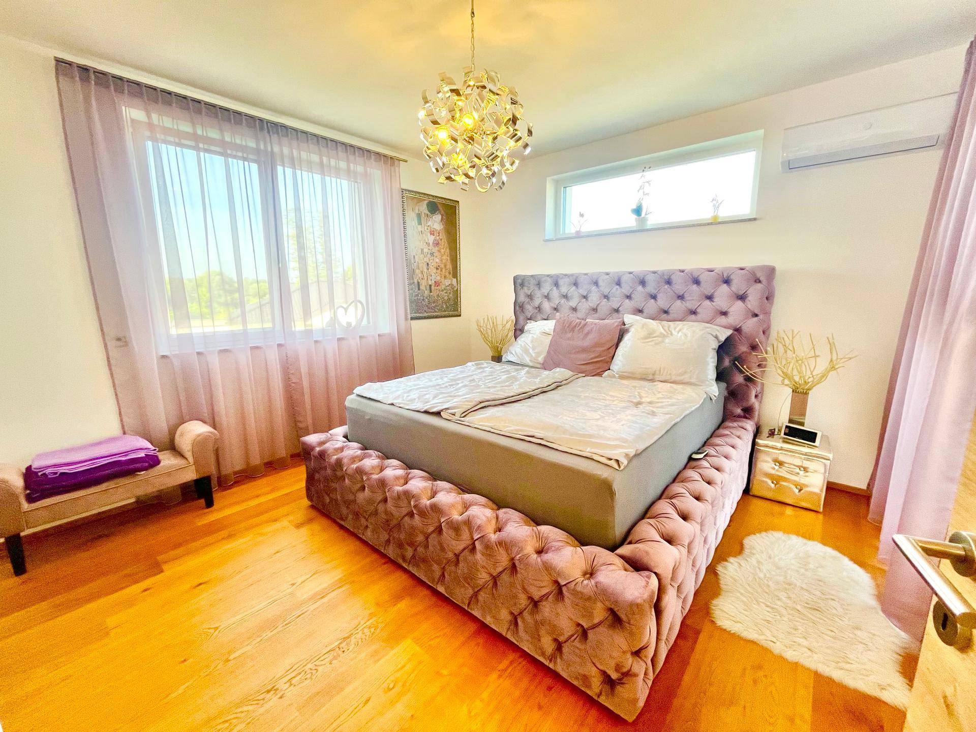 Stilvolles Schlafzimmer mit großem Bett, Holzboden und viel Tageslicht.