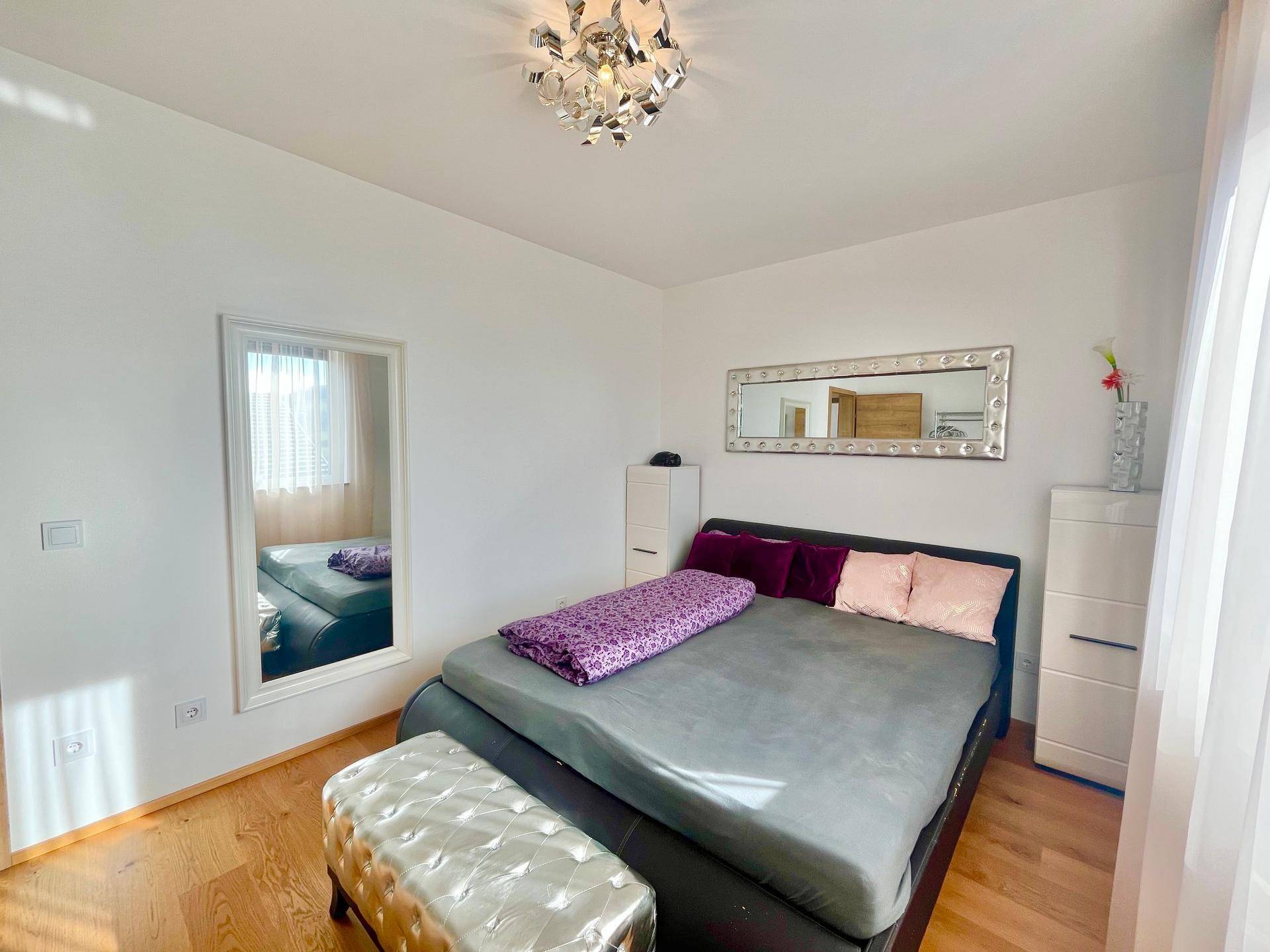 Helles Schlafzimmer mit großem Bett, Spiegel und Holzboden.