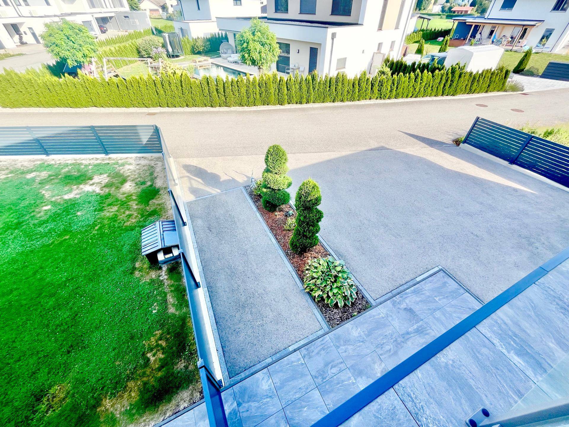 Blick vom Balkon auf die gepflegte Vorgartenlandschaft und die Zufahrt des Anwesens.