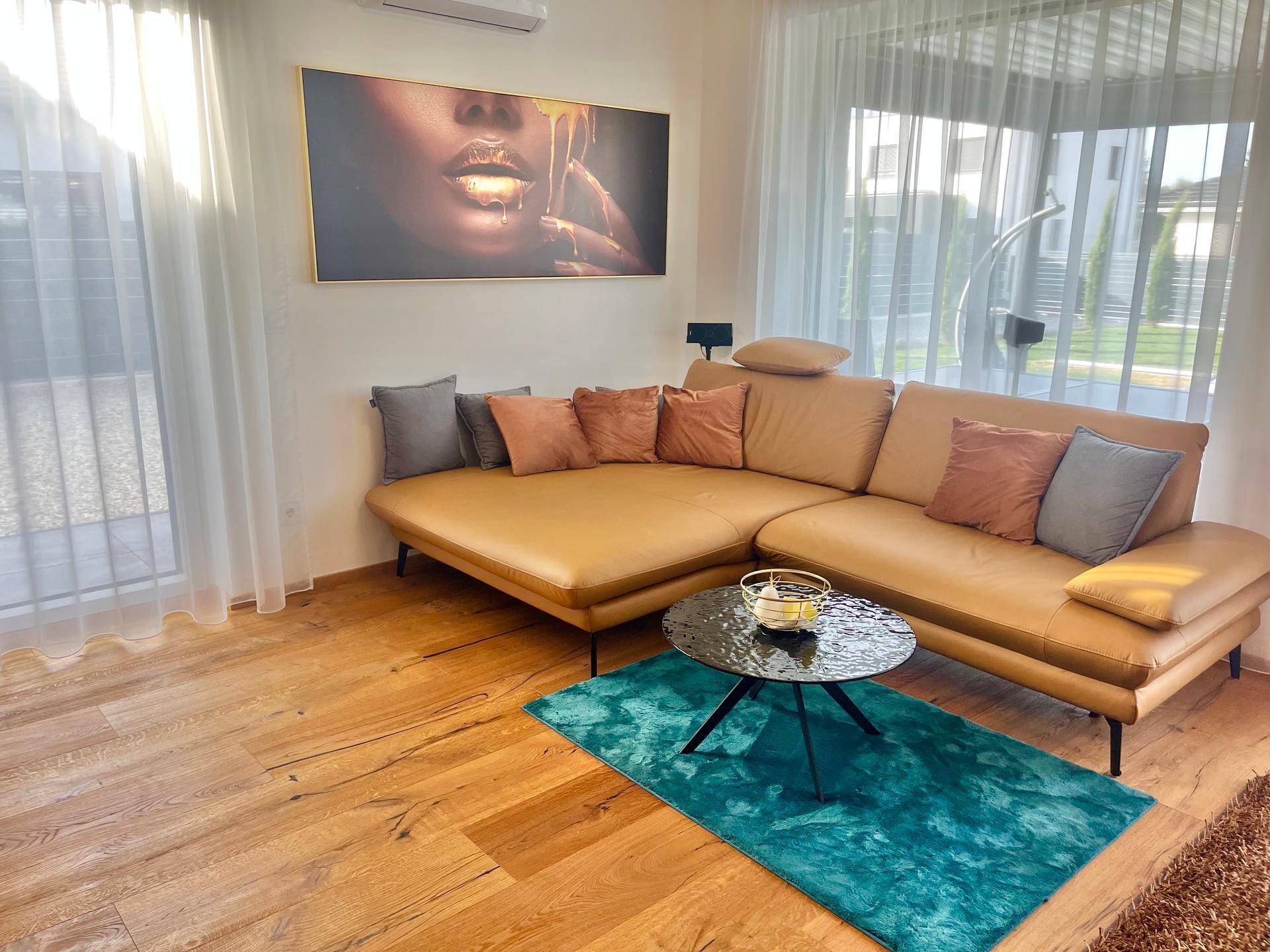 Gemütlicher Wohnbereich mit beiger Eckcouch, modernem Couchtisch und großem Fenster.