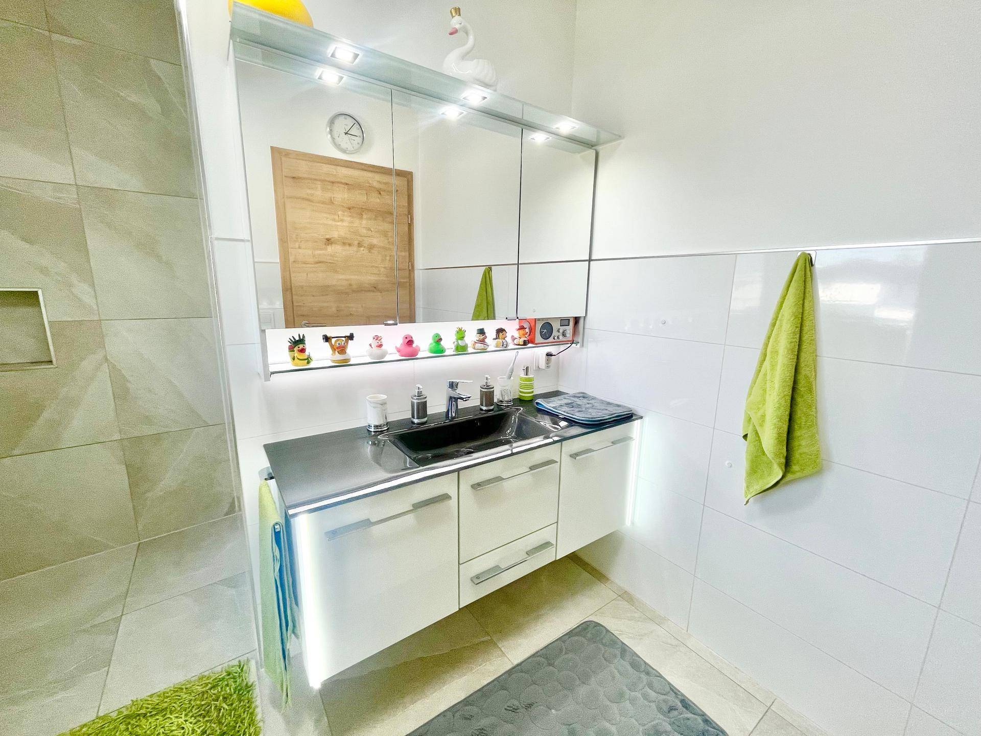 Moderner Waschtisch mit Einzelwaschbecken, Spiegelschrank und weißen Fliesen im Badezimmer.