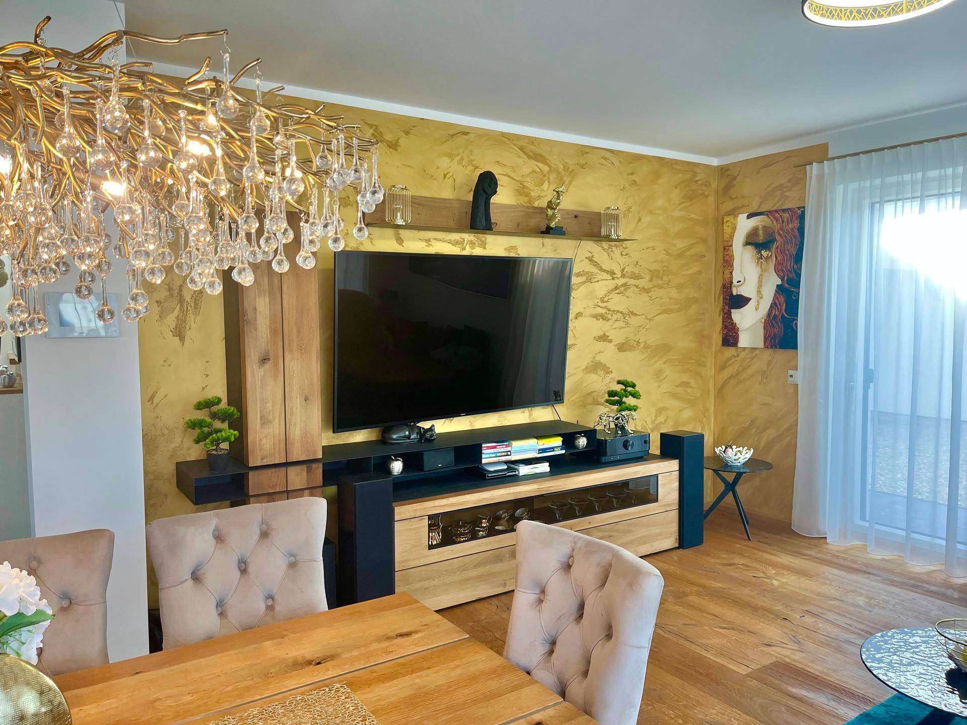 Eleganter Wohn-Essbereich mit Holztisch, TV-Möbel und goldener Akzentwand.