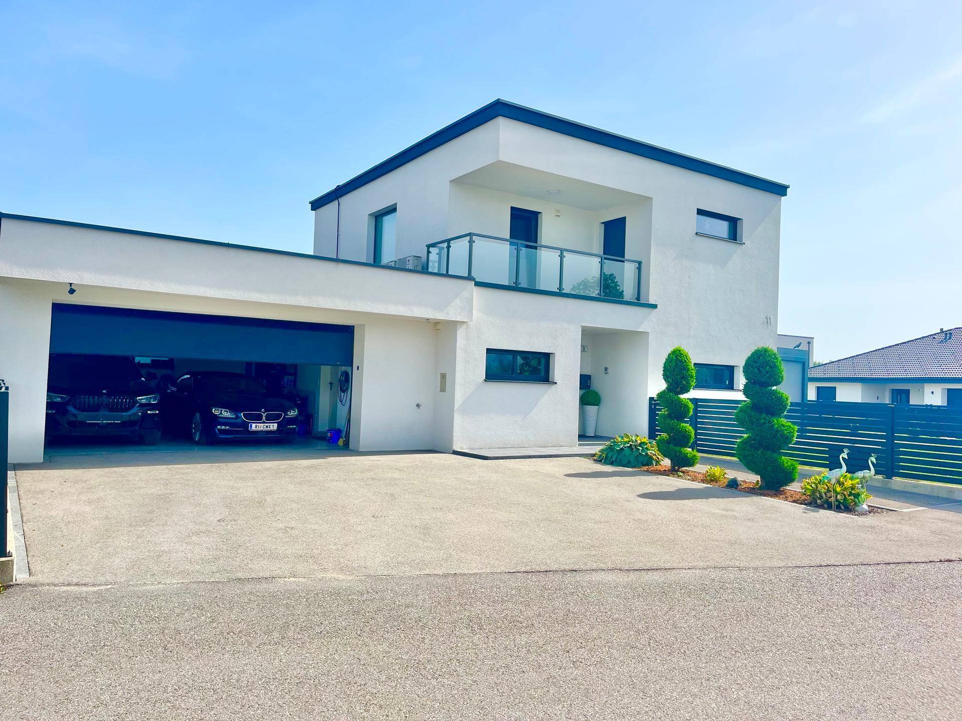 Elegantes Einfamilienhaus mit integrierter Doppelgarage und zwei Fahrzeugen.