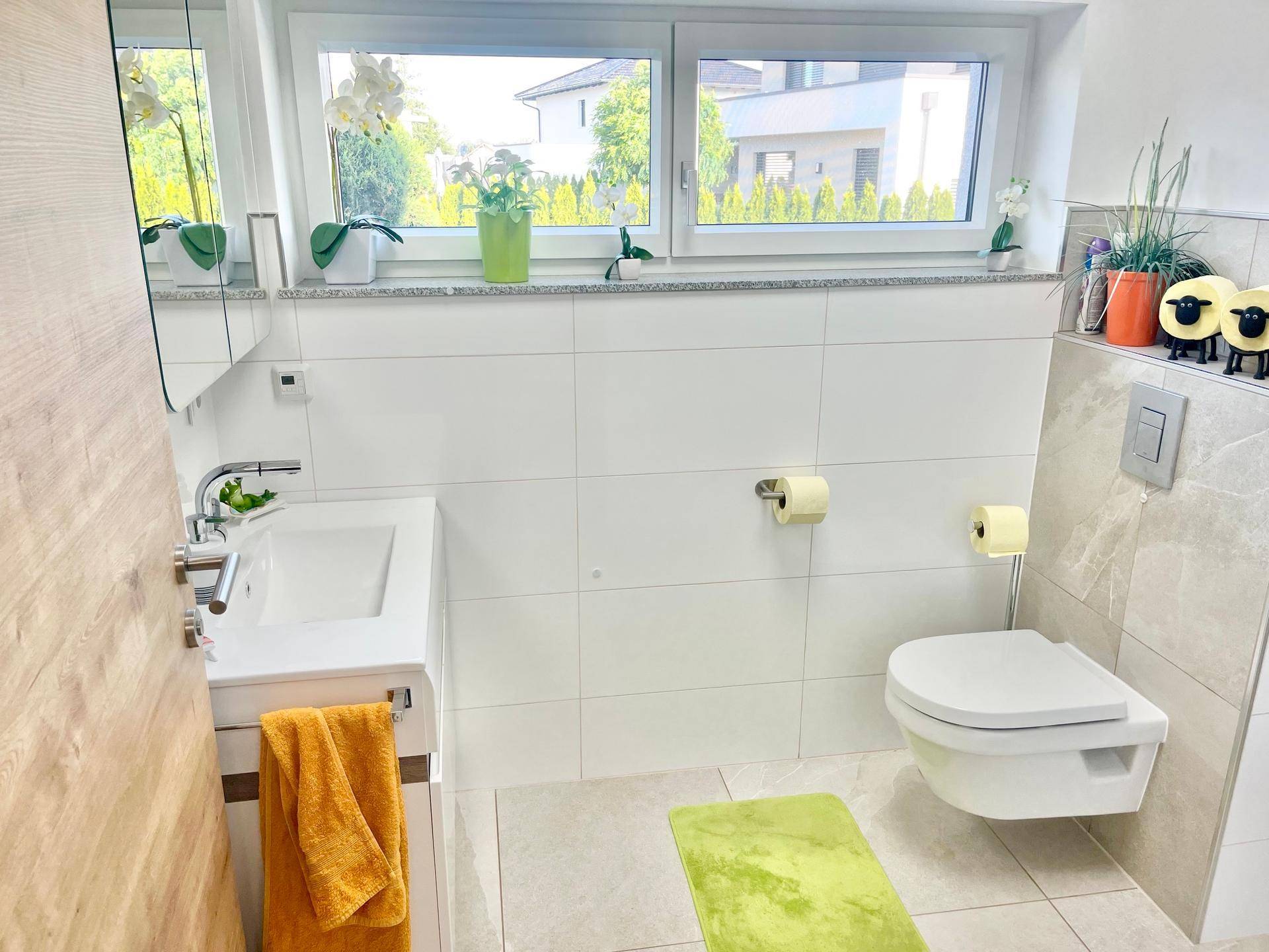 Helles Badezimmer mit Fenster, modernem Waschtisch und Wand-WC.