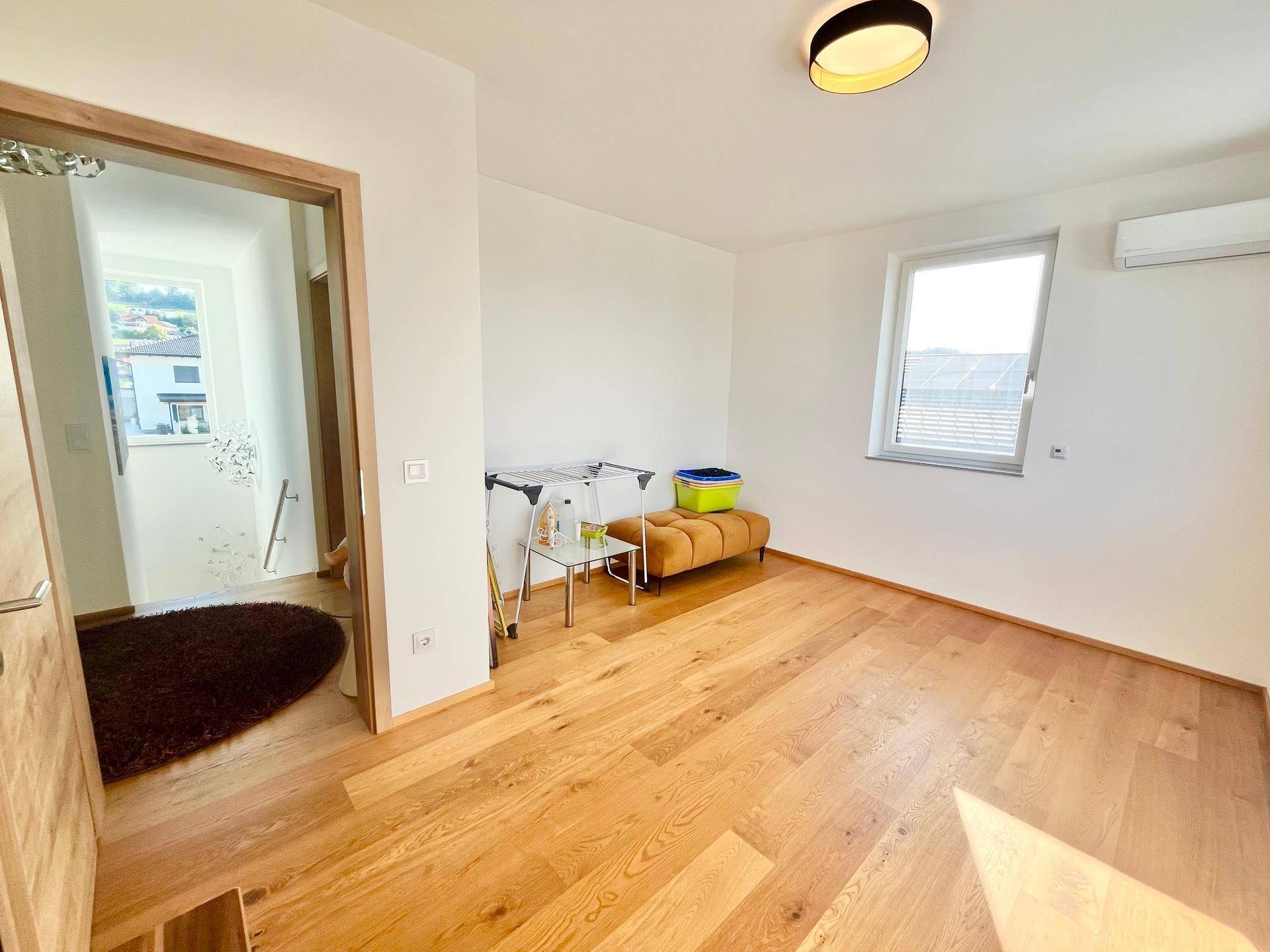 Lichtdurchflutetes Schlafzimmer mit Holzboden und Zugang zum Flur.