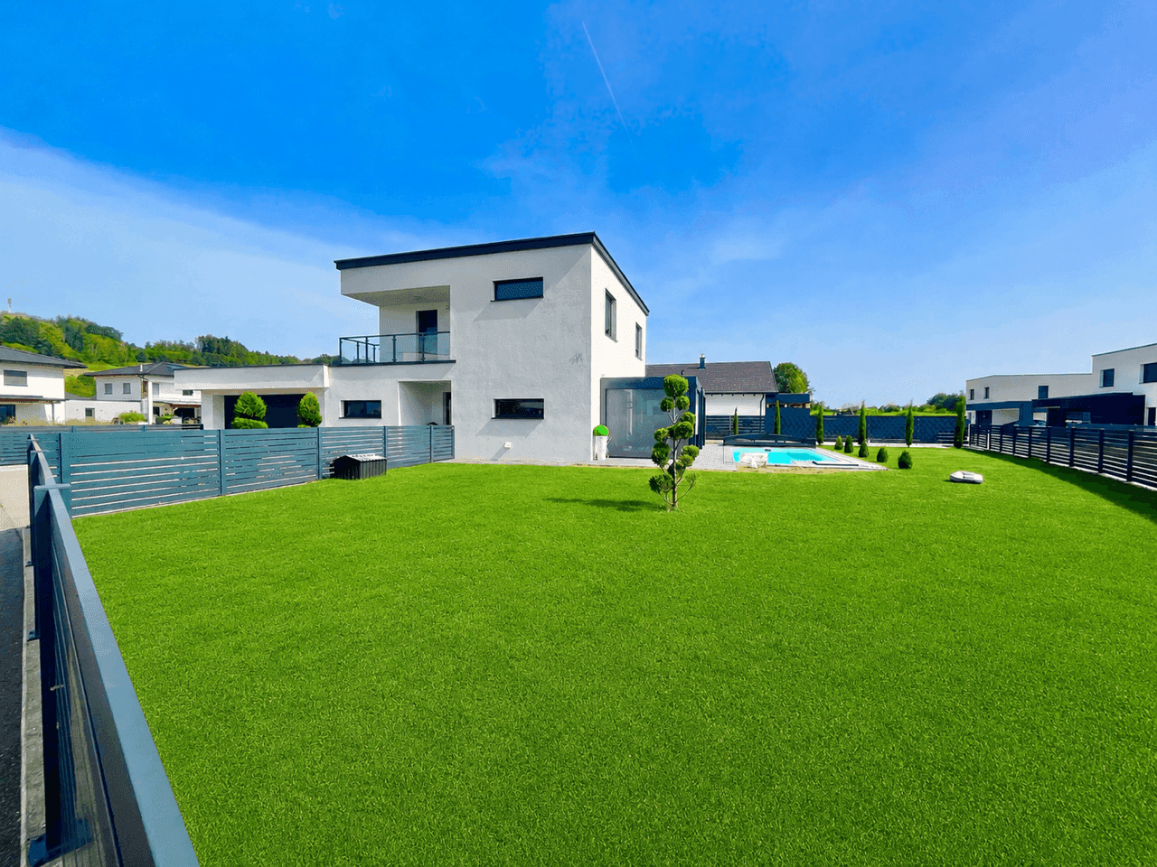 Gepflegter Garten mit weitläufiger Rasenfläche und modernem Poolbereich.