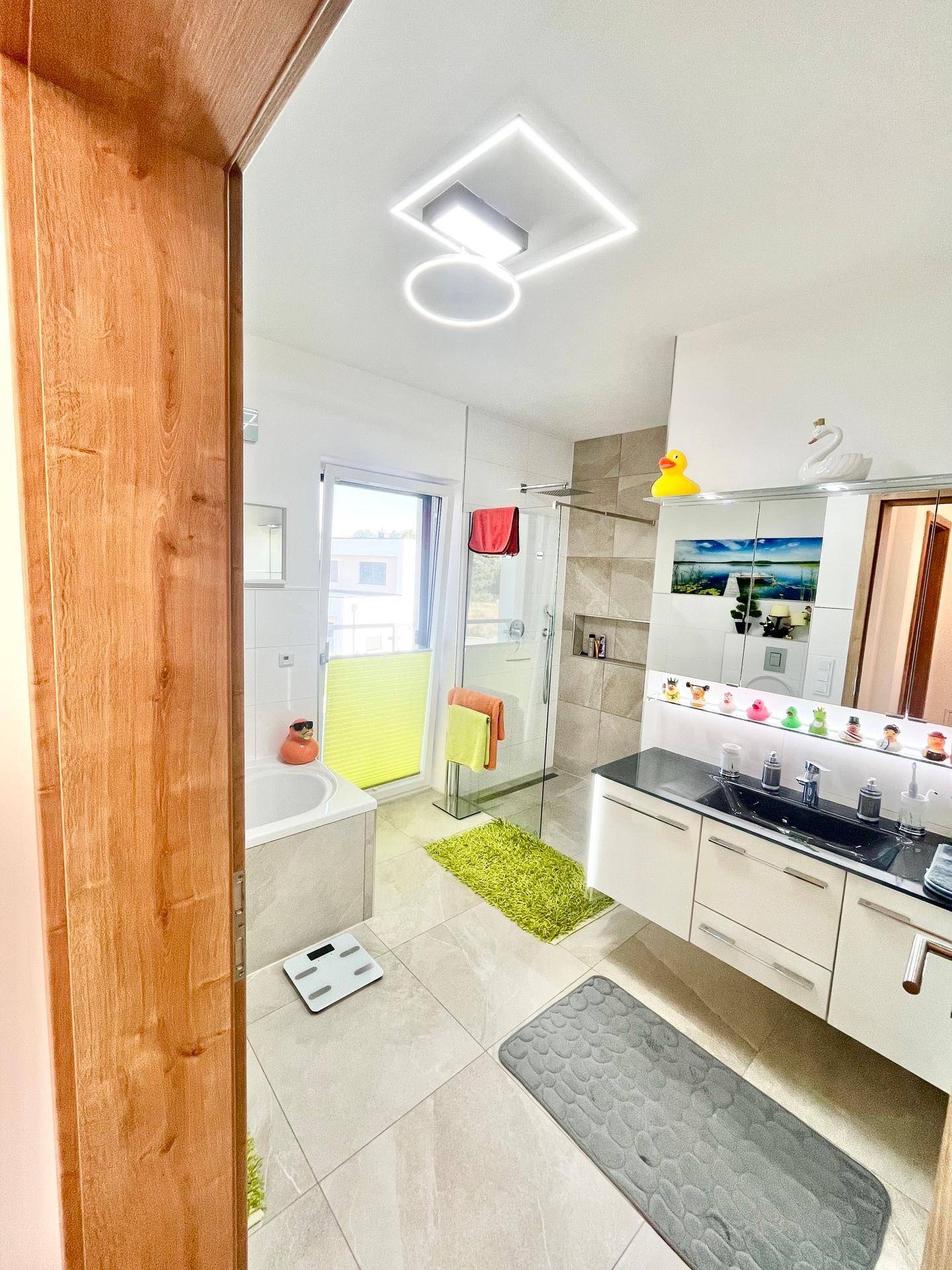 Modernes Badezimmer mit Badewanne, begehbarer Dusche, Einzelwaschbecken und Fenster für Tageslicht.
