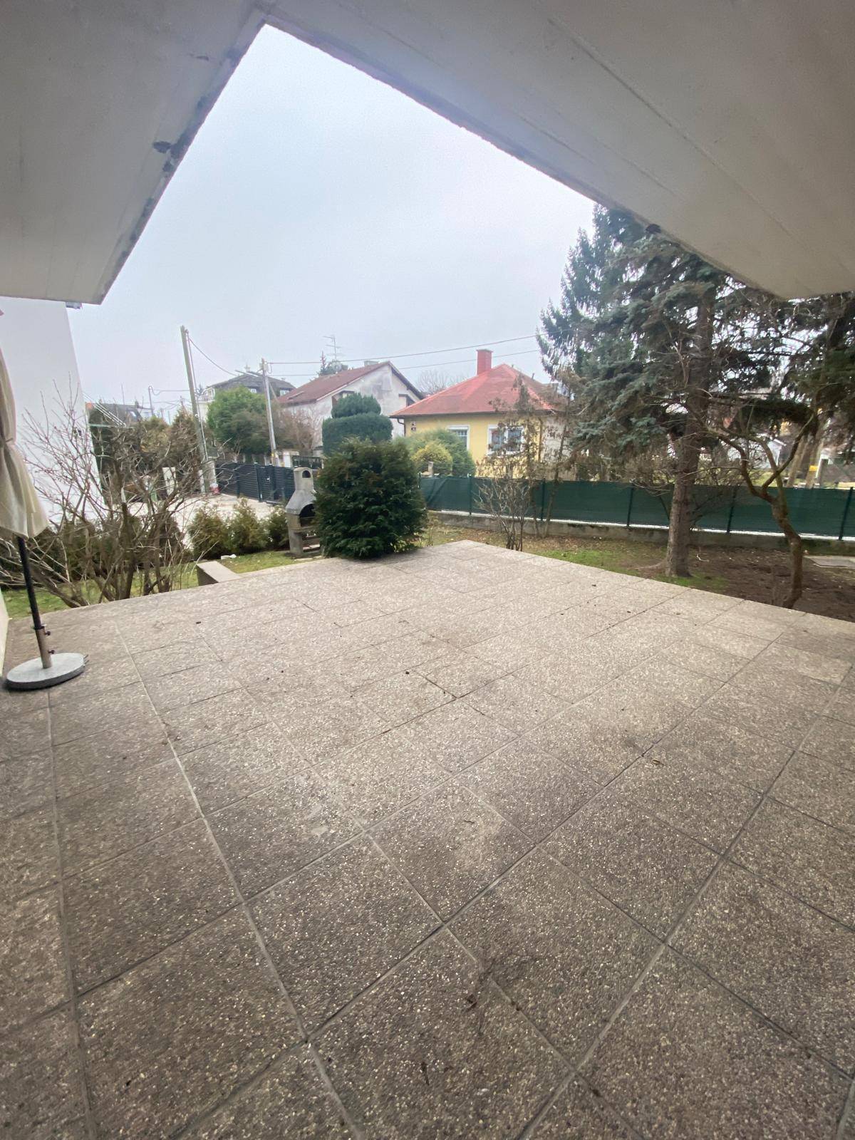 Große gepflasterte Terrasse mit Blick auf den Garten und die umliegende Nachbarschaft.
