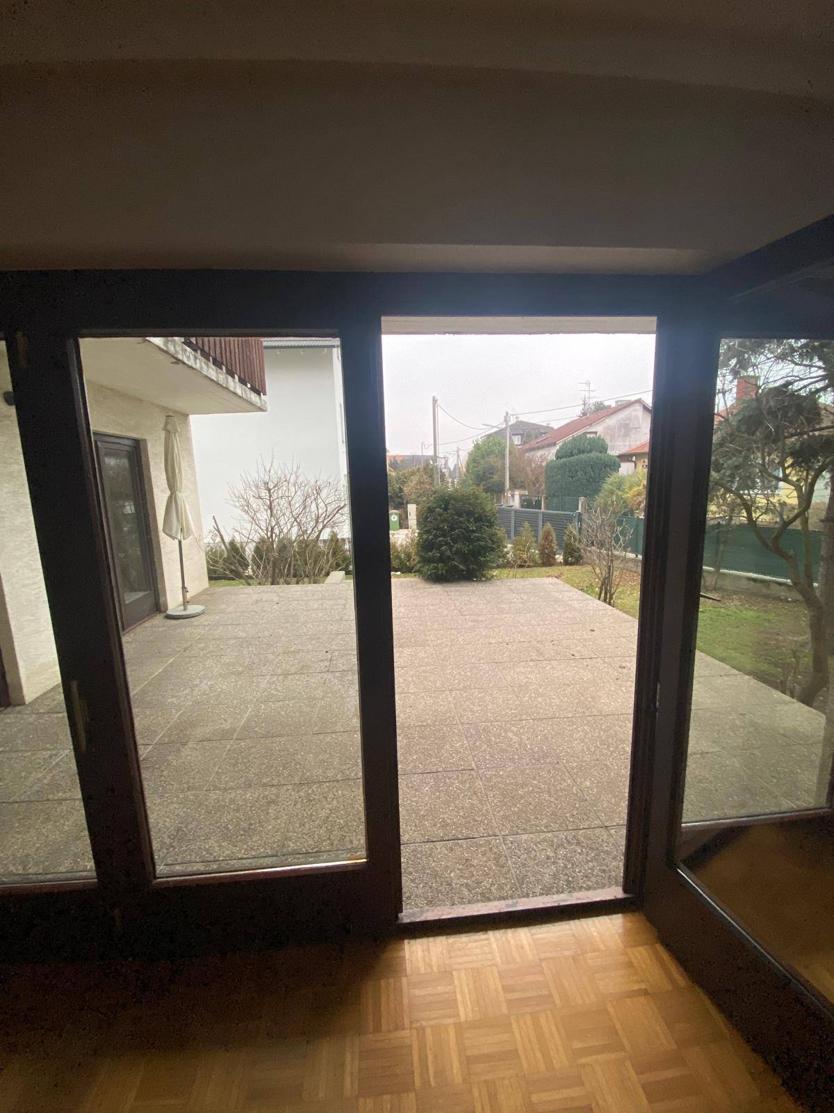 Blick aus einem Zimmer durch große Glastüren auf eine geräumige Außenterrasse.