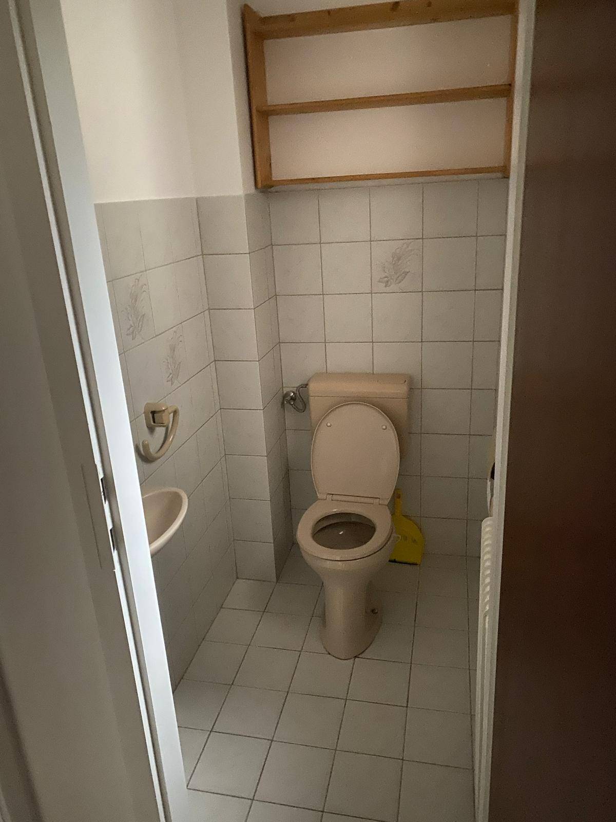 Kleines Gäste-WC mit Fliesen, Waschbecken und WC, ausgestattet mit Heizkörper.