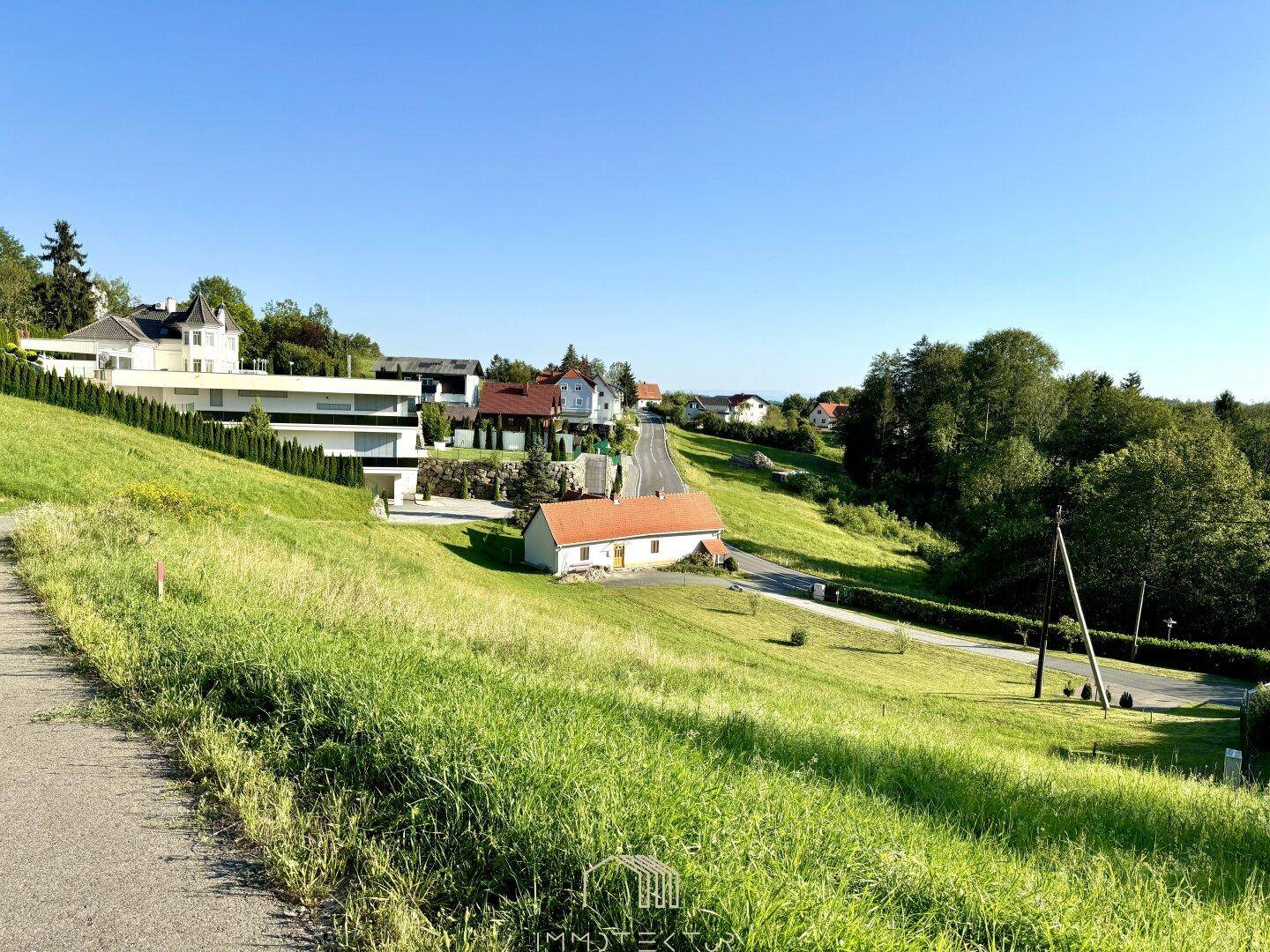 Panoramablick auf die ländliche Umgebung mit modernen und traditionellen Wohnhäusern und viel Grün.