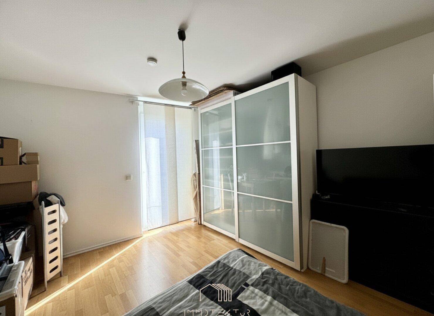 Schlafzimmer mit großem Schiebetürenschrank und hellem Holzfußboden.