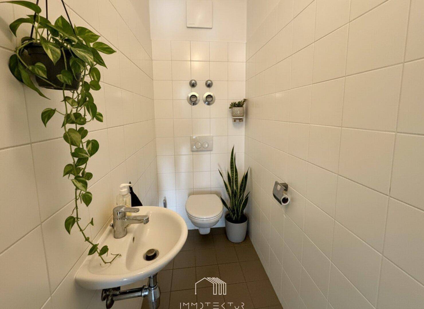 Separates Gäste-WC mit Waschbecken und weißen Wandfliesen.