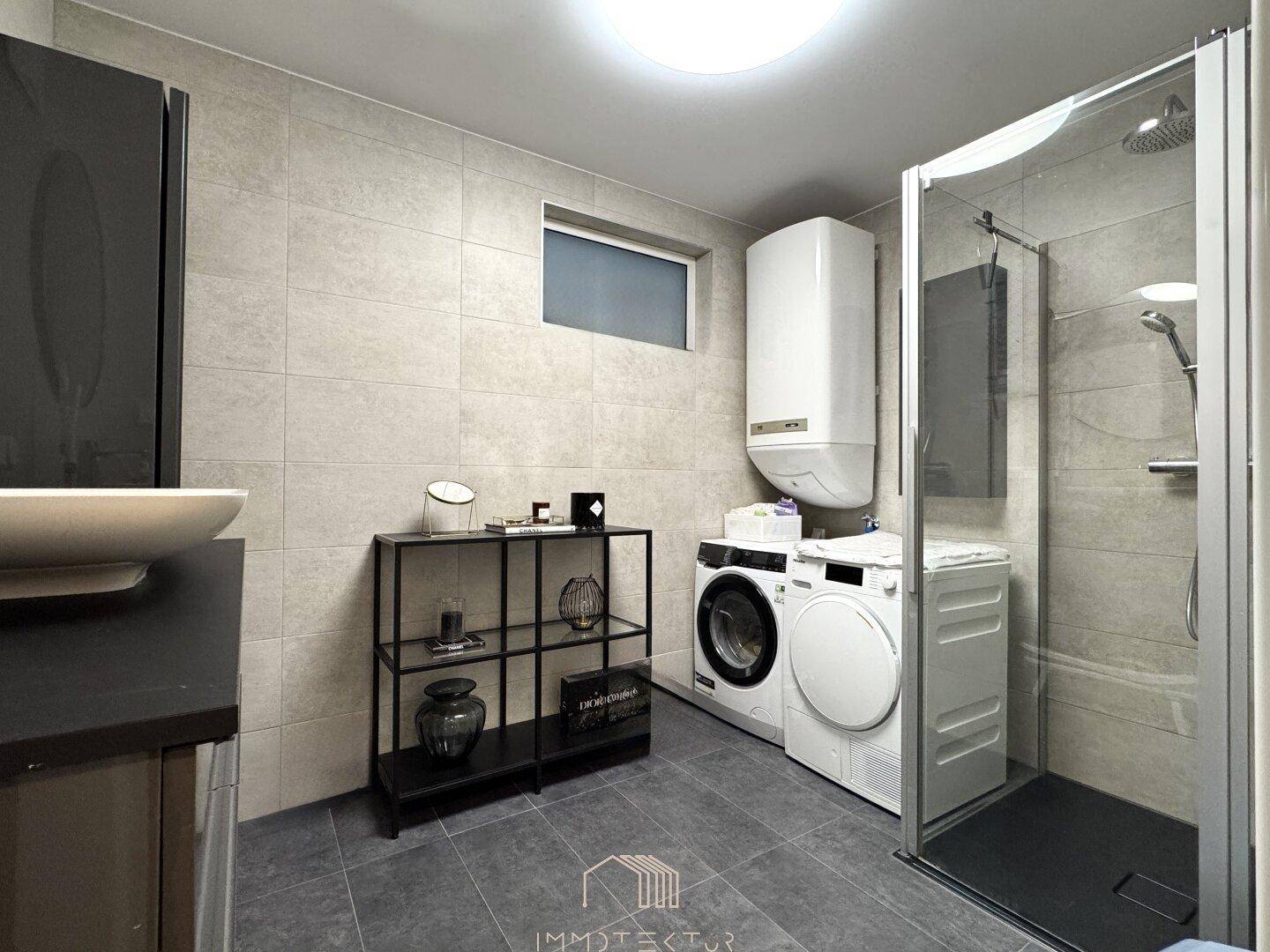 Funktionales Badezimmer mit ebenerdiger Dusche, Waschmaschine, Trockner und Fenster.