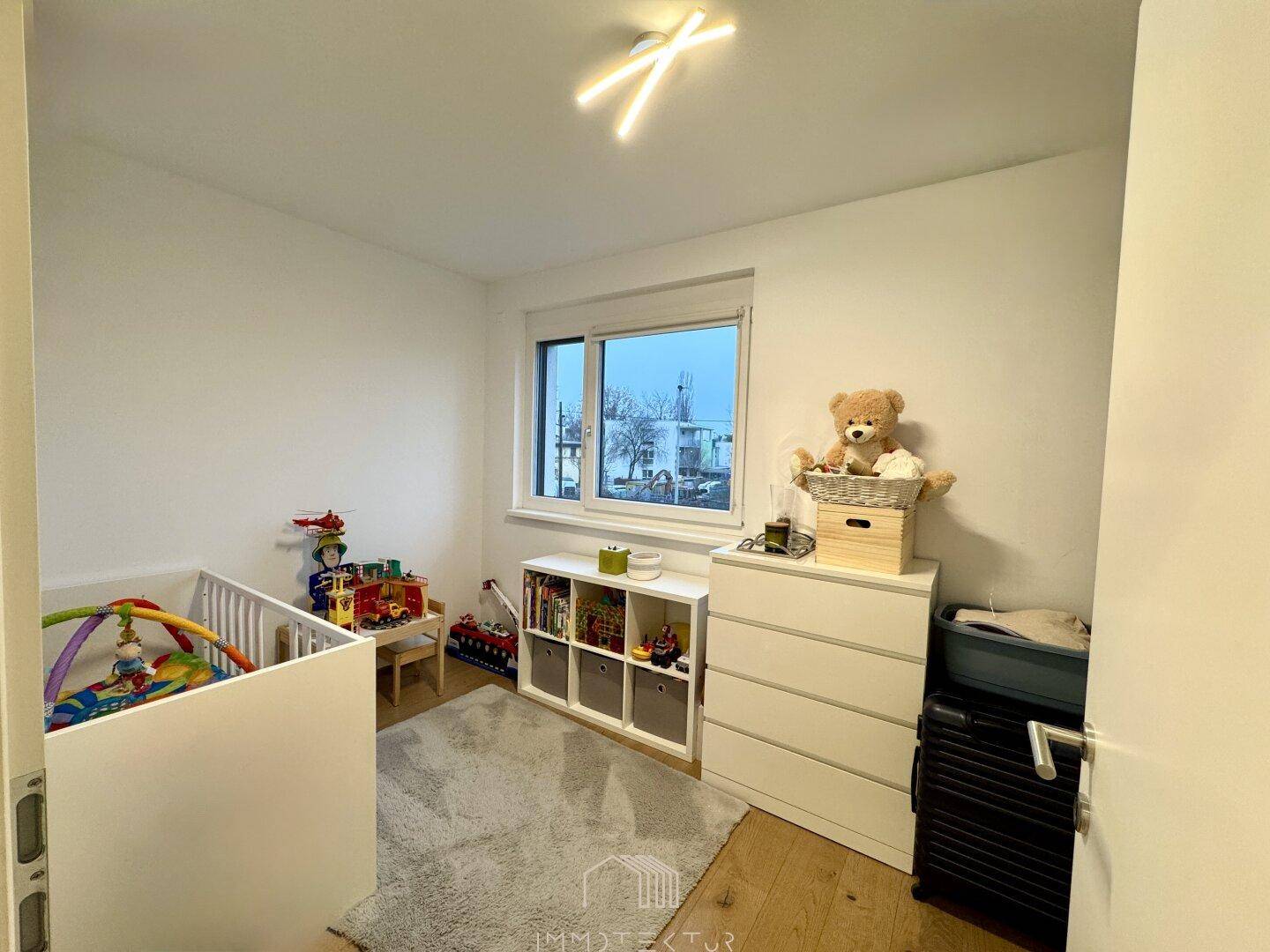 Kinderzimmer mit Babybett, Kommode und Fenster, ideal für ein kleines Kind.