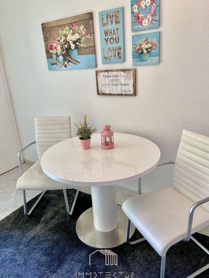 Gemütlicher Essbereich mit rundem Tisch und farbenfroher Wanddekoration.