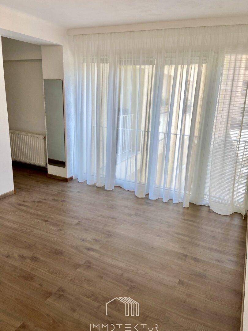 Leerer Raum mit Laminatboden und Zugang zu einem Balkon, ideal für individuelle Gestaltung.