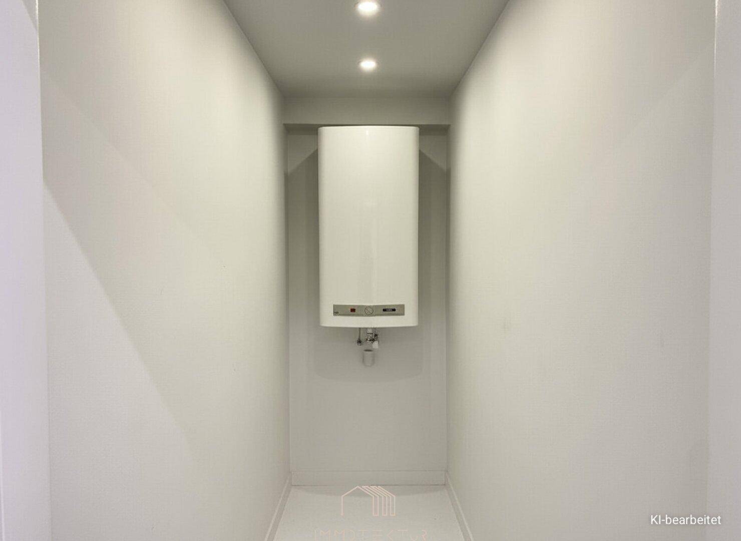 Kleiner Hauswirtschaftsraum mit Warmwasserbereiter und schlichten weißen Wänden.