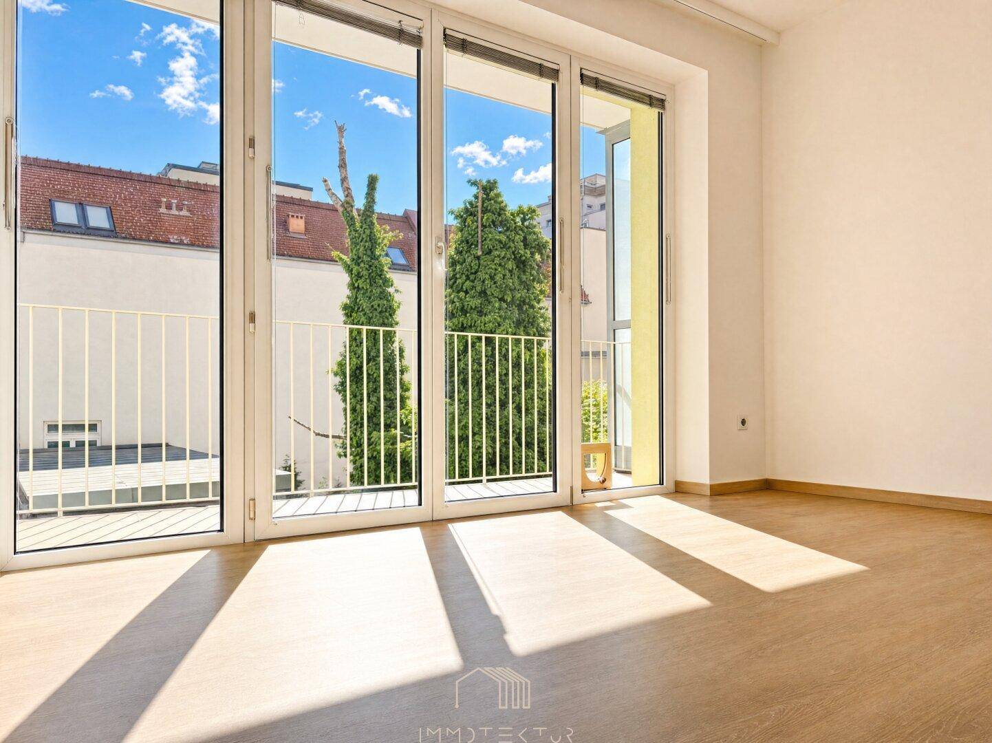 Heller Wohnraum mit großen Fenstern, die viel Tageslicht hereinlassen und Blick ins Grüne bieten.
