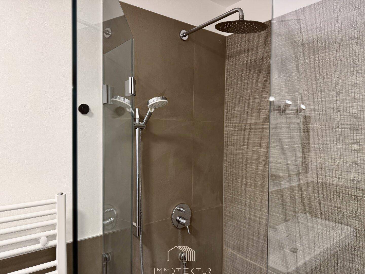 Nahaufnahme der modernen begehbaren Dusche mit Regenduschkopf und Handbrause.