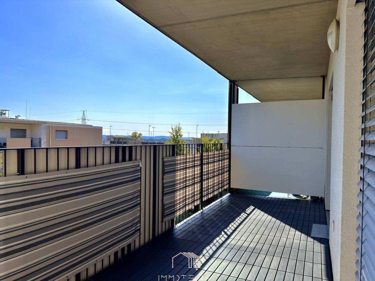 Heller Balkon mit Holzboden und weitem Blick in die Landschaft.
